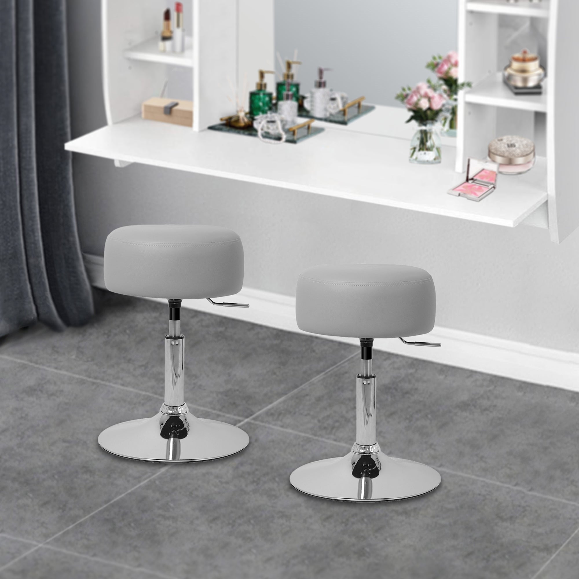 Two gray bar stools with round seat in front of a mirror and a white shelf.