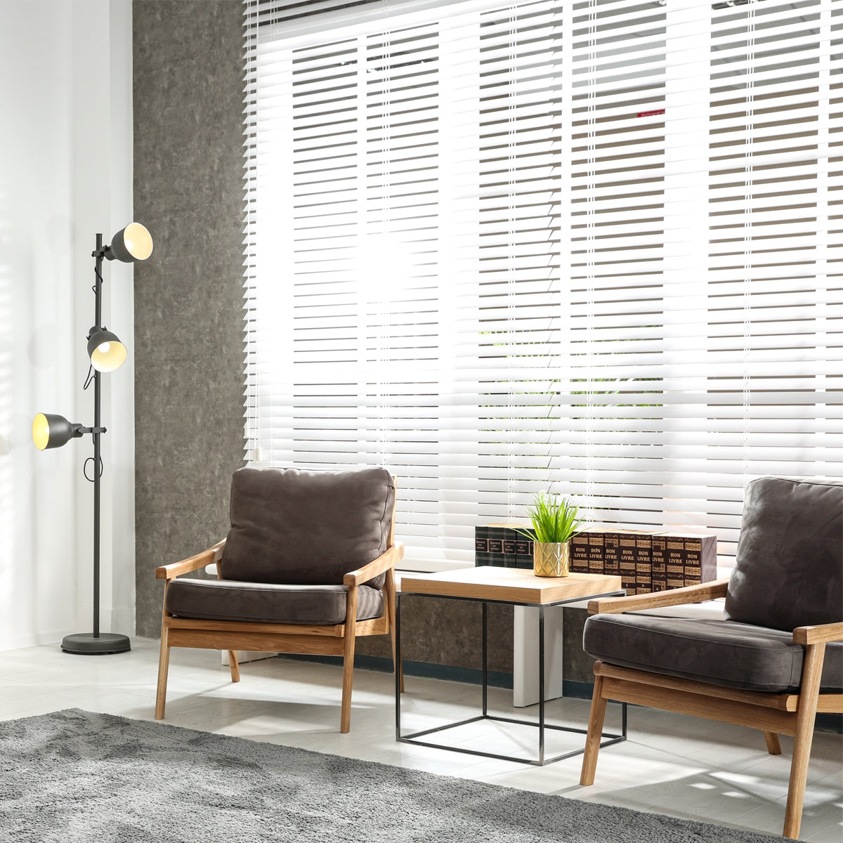 Wohnzimmer mit weißen Jalousien, zwei Sessel und eine Stehlampe.