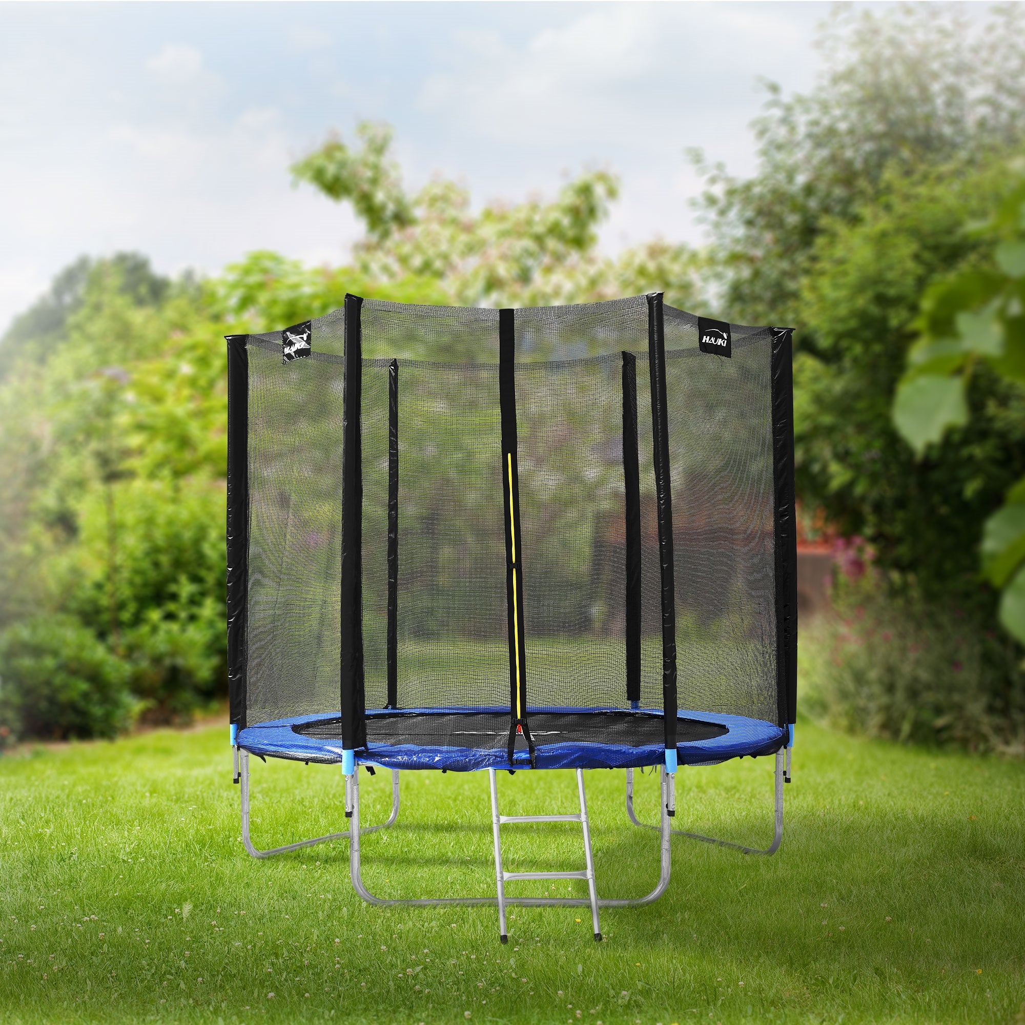 Trampolína s ochrannou sítí a žebříkem na zahradě, obklopená stromy.