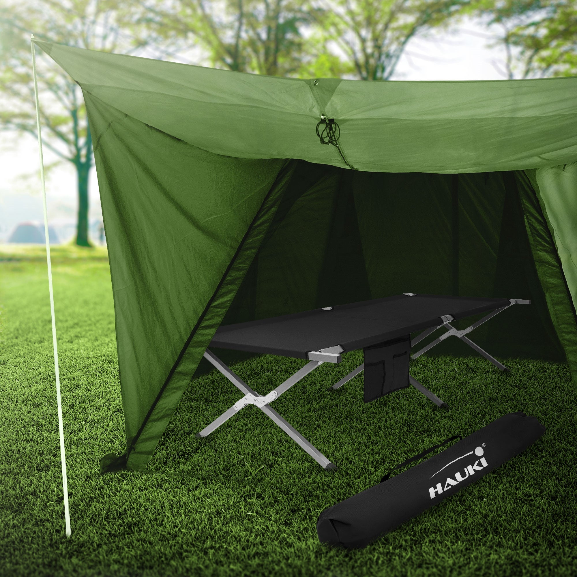 Campingtisch unter einem grünen Zelt, mit einer Tragetasche daneben.
