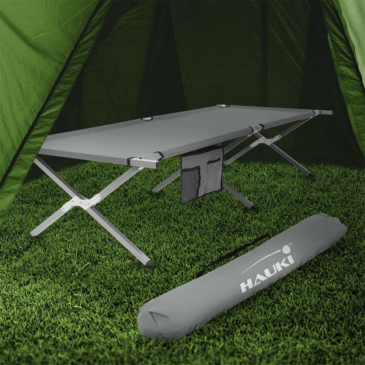 Camp bed in a tent with a carry bag beside it.