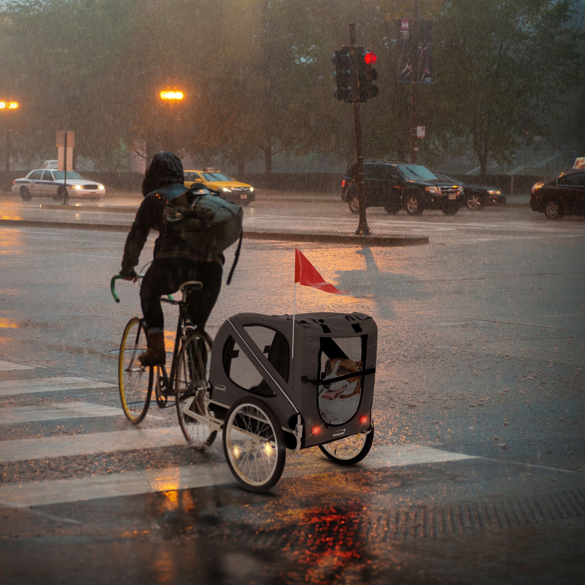 Fahrrad mit Anhänger bei Regen an einer Straßenecke, Ampel im Hintergrund.