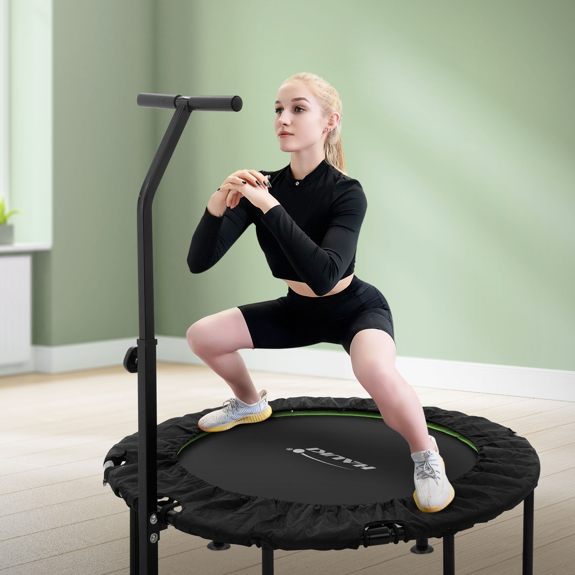 Frau in Sportkleidung macht Kniebeugen auf einem Trampolin.