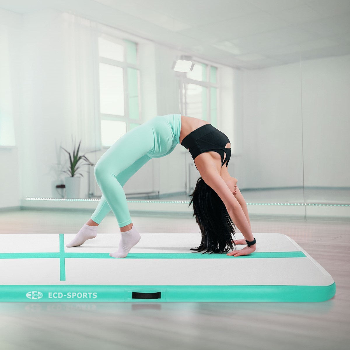 Person in athletic clothing does a backbend on a mint-green exercise mat.