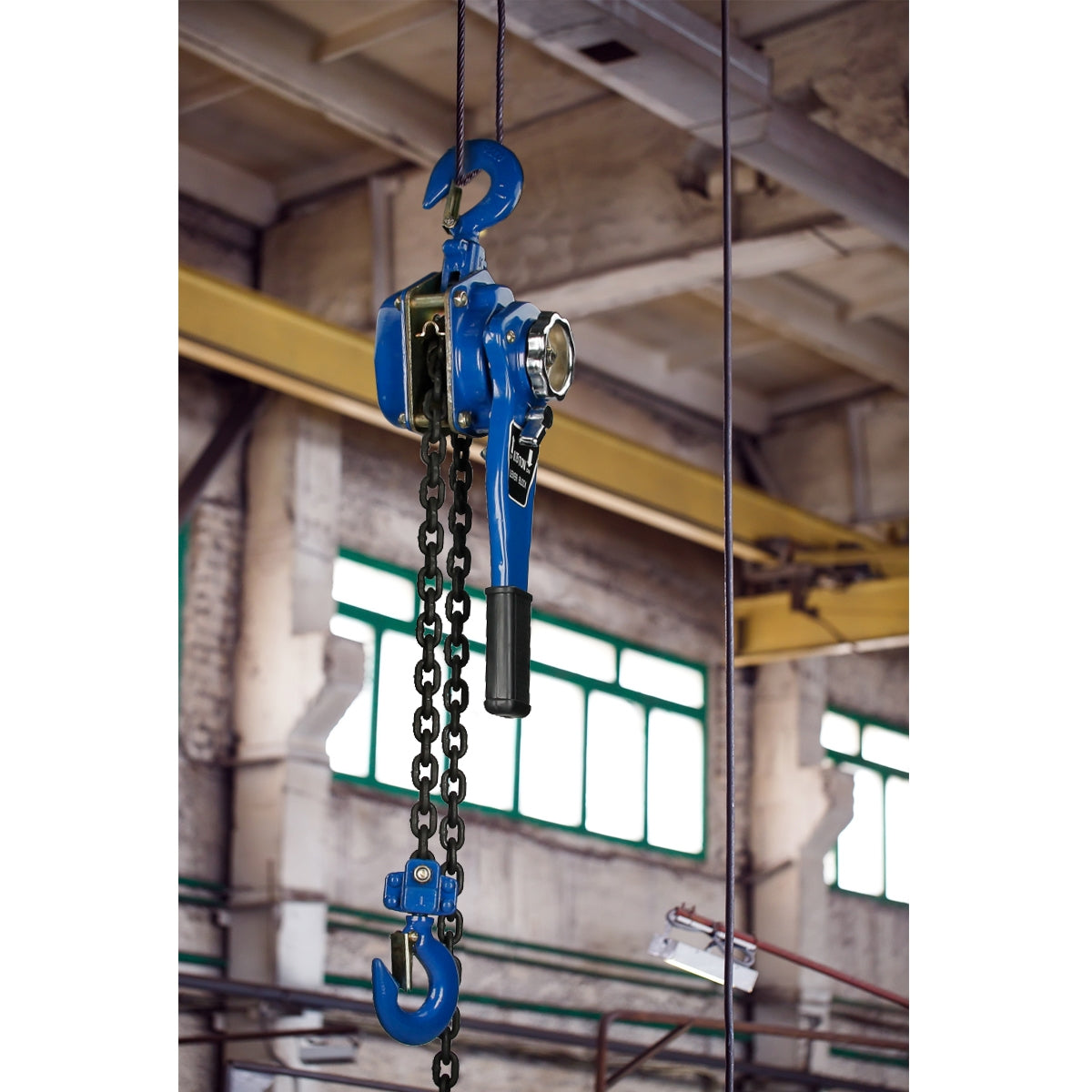 Ein blauer Kettenzug hängt von der Decke in einer Industrieumgebung.