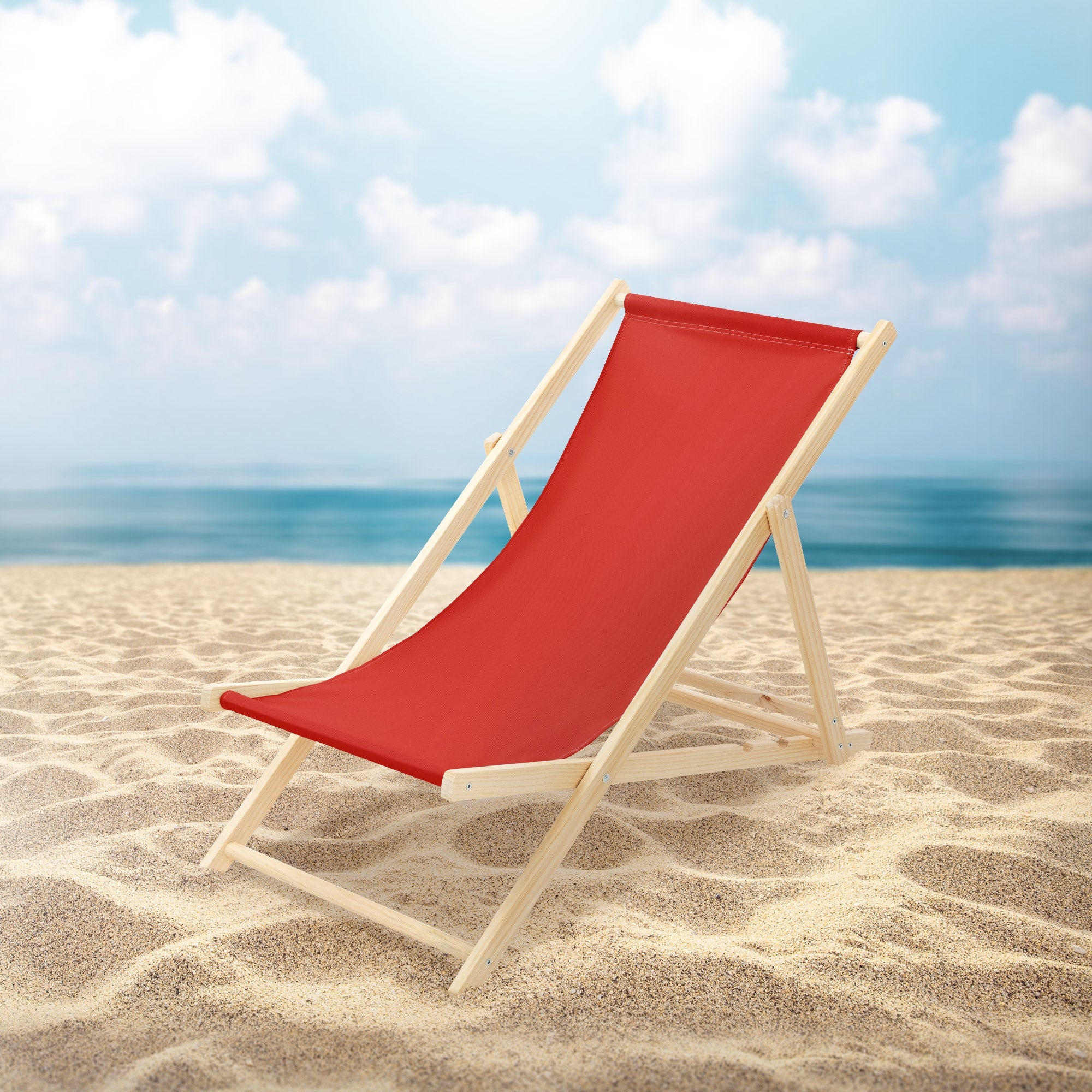 Roter Liegestuhl auf einem Sandstrand mit Meer im Hintergrund.