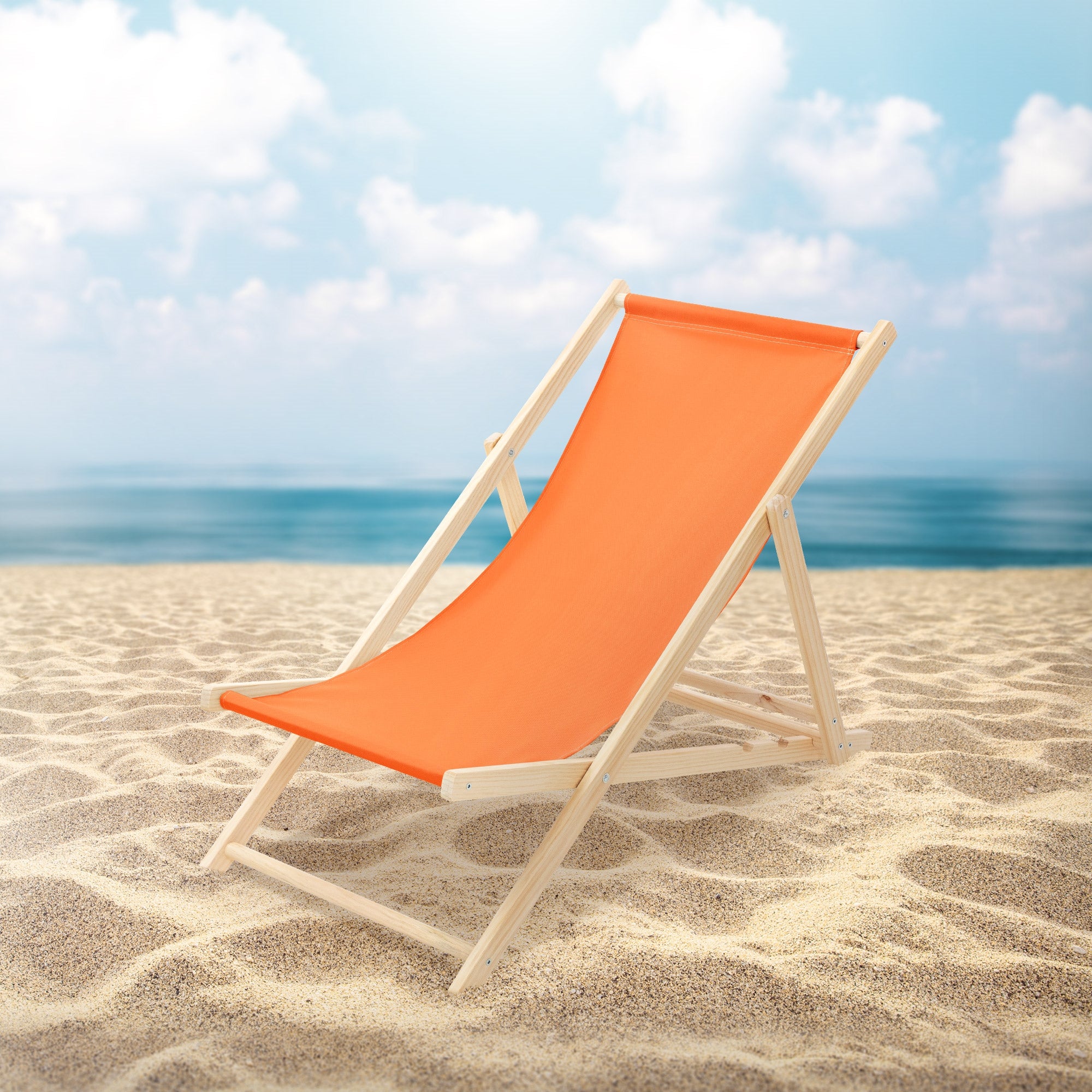 Oranger Liegestuhl auf einem Sandstrand mit Meer im Hintergrund.