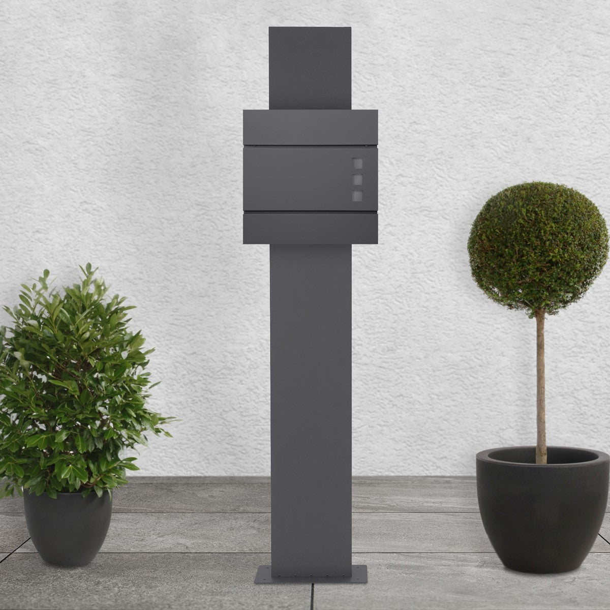 Gray mailbox on a pedestal, surrounded by two potted plants.