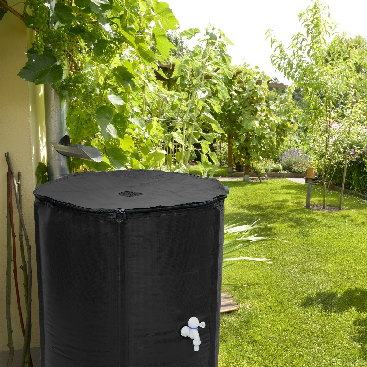 Schwarzer Wassertank im Garten, umgeben von Pflanzen und Bäumen.