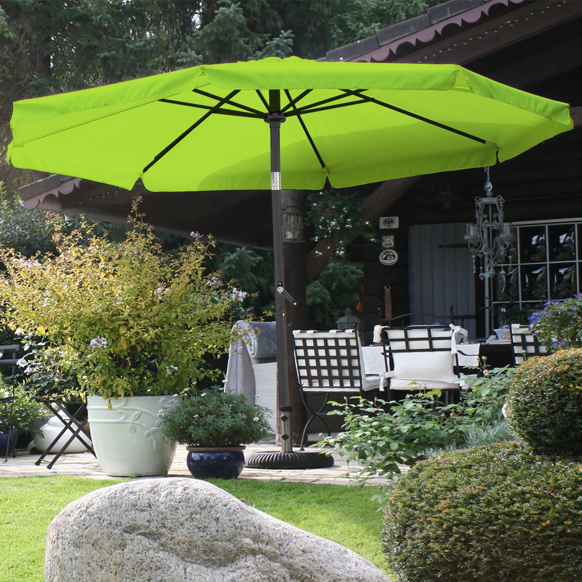 Parasol vert sur une terrasse avec des plantes et des meubles.