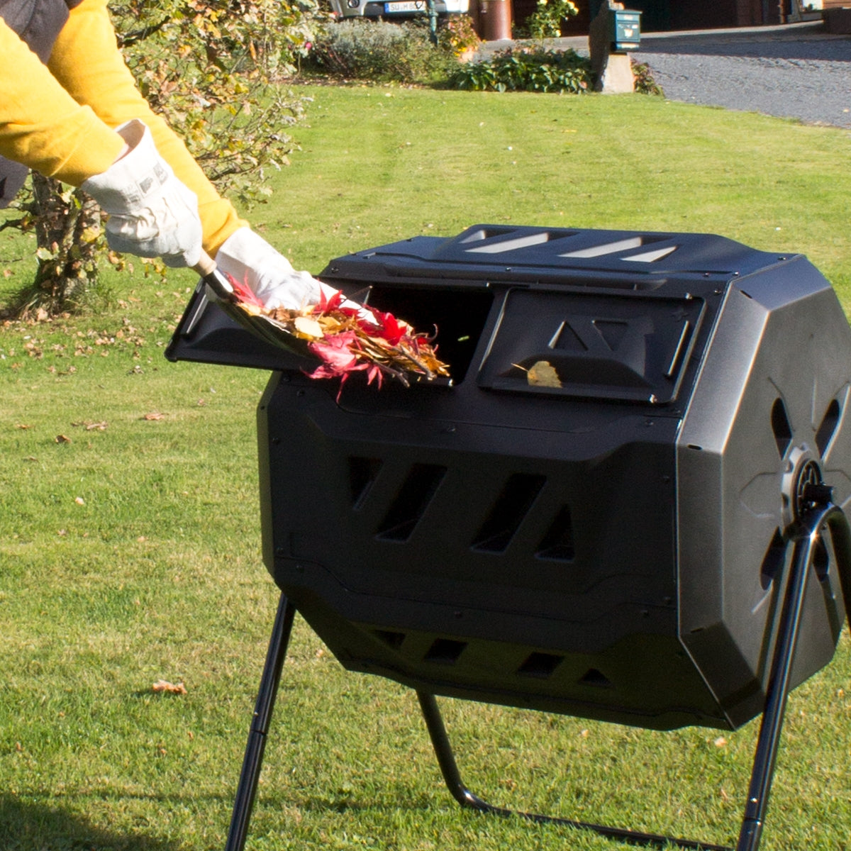 Une personne nourrit un composteur avec des feuilles.