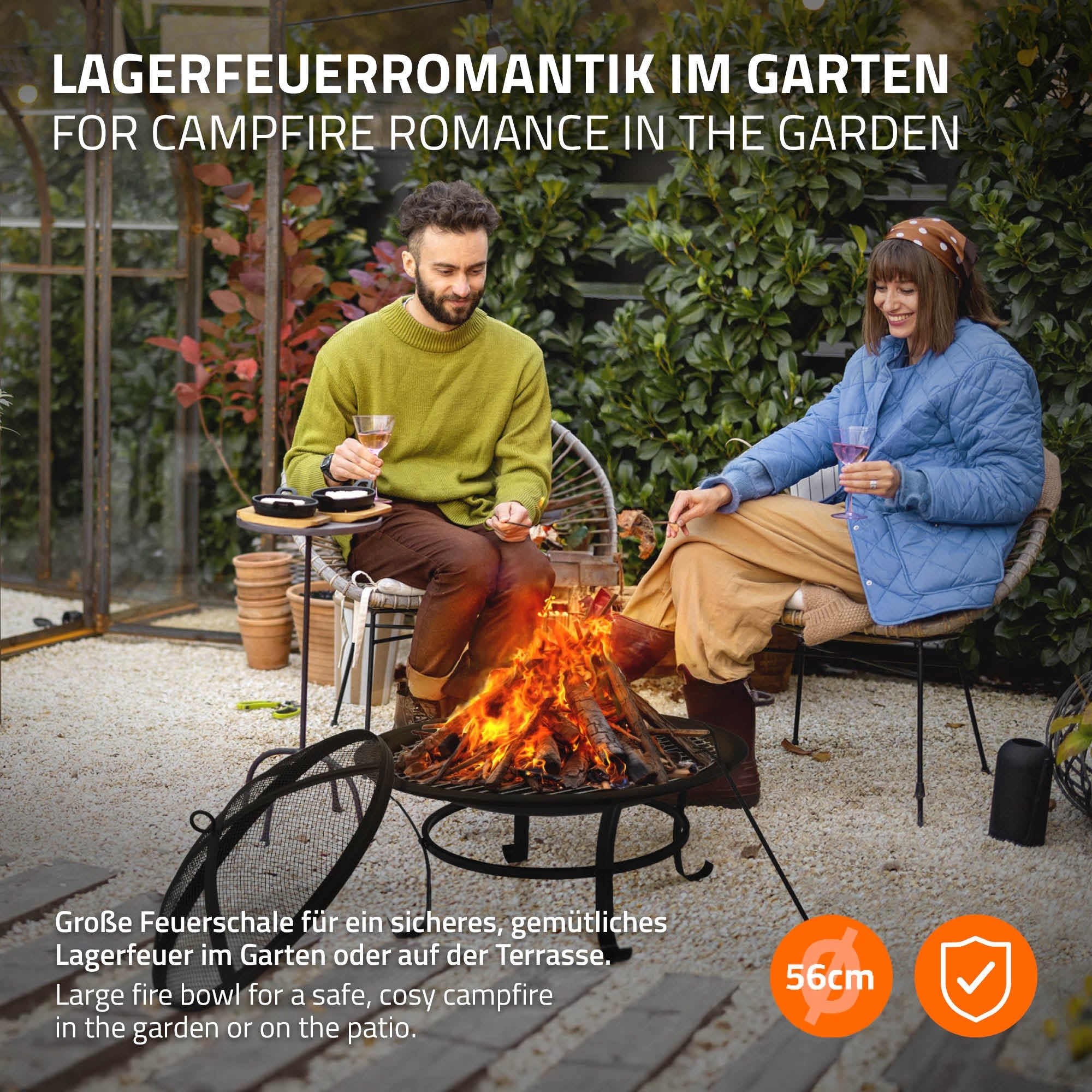 Paar sitzt am Lagerfeuer im Garten, umgeben von Stühlen.