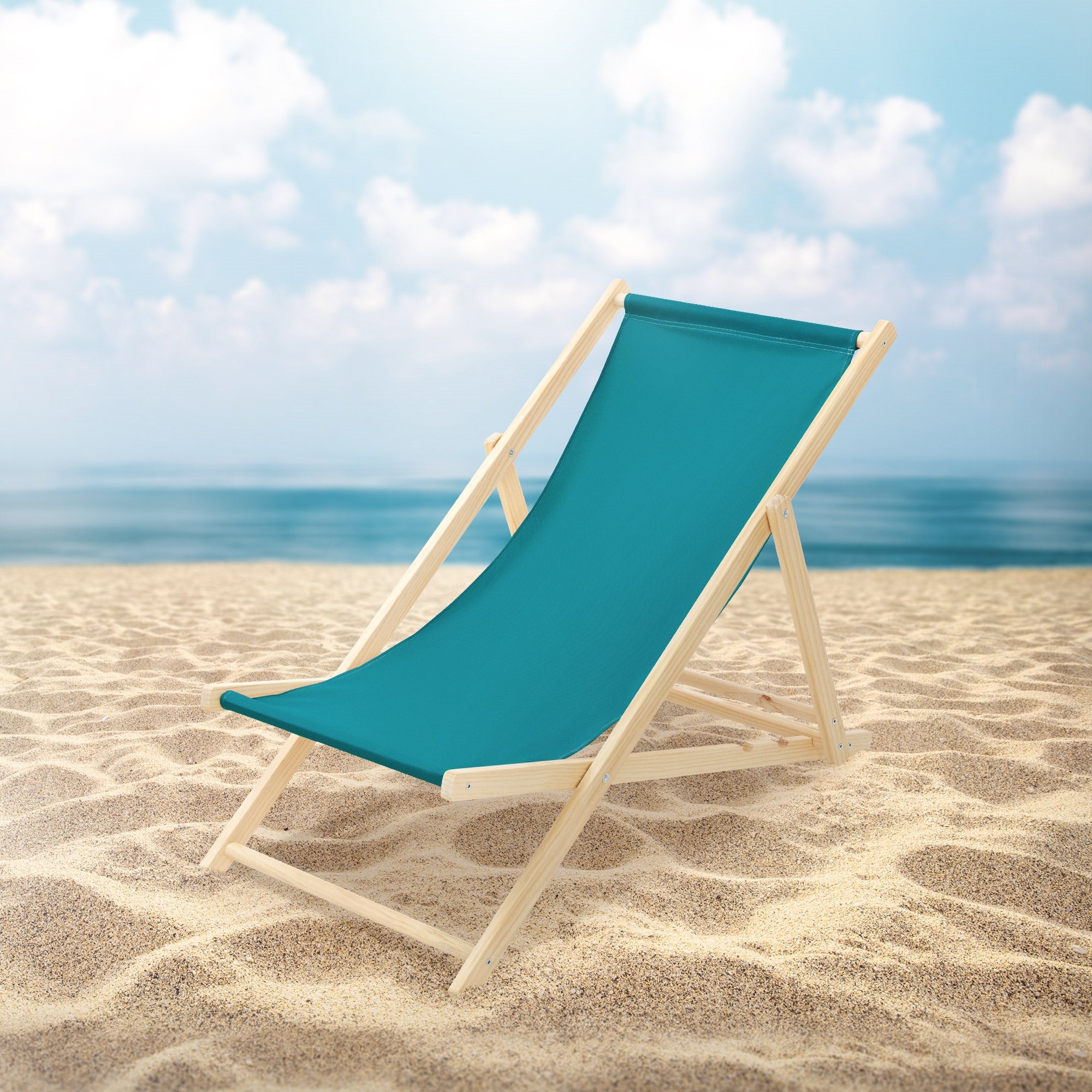 Liegestuhl am Strand mit Meer und Wolken im Hintergrund.