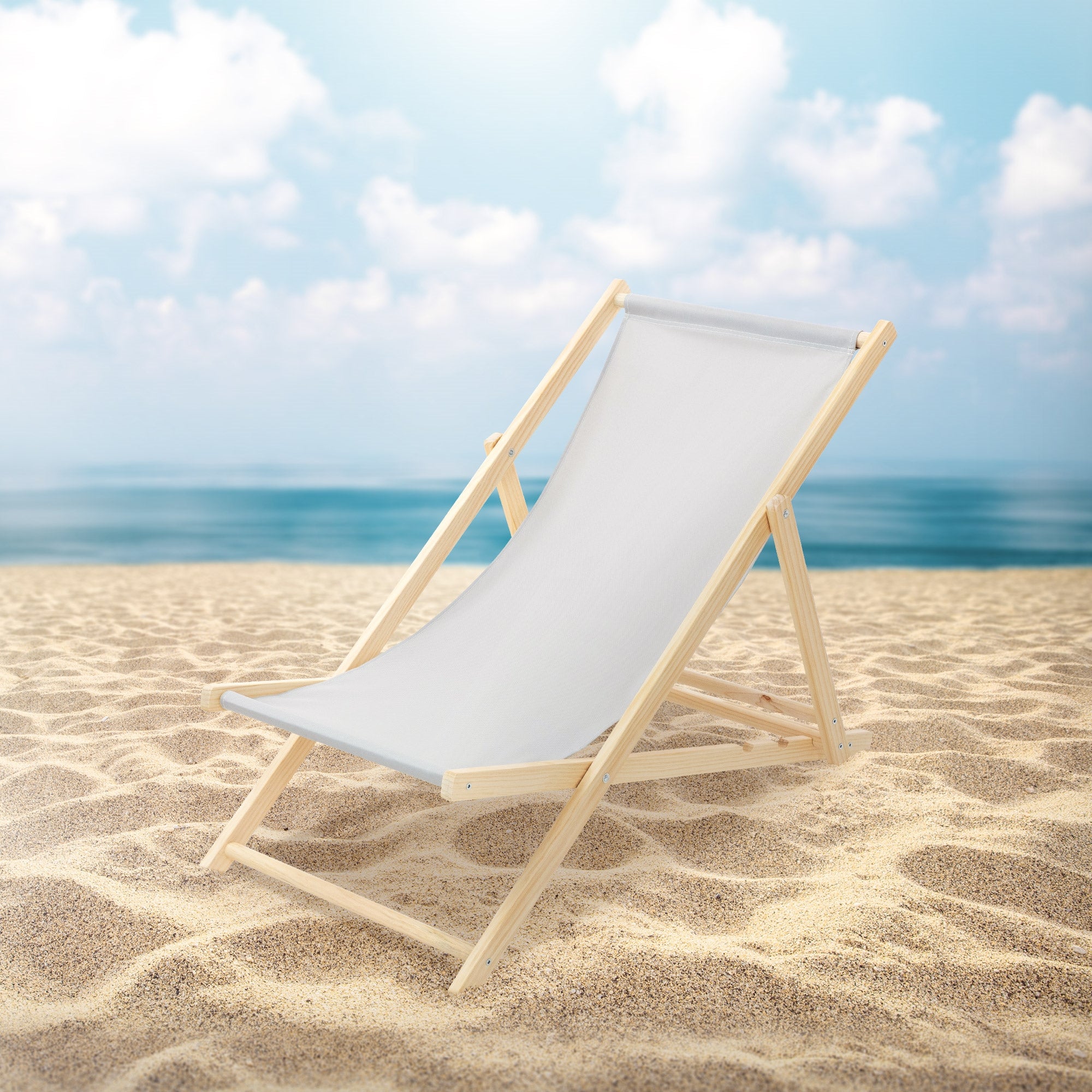 Holzliege am Strand mit Meer im Hintergrund und blauen Himmel.