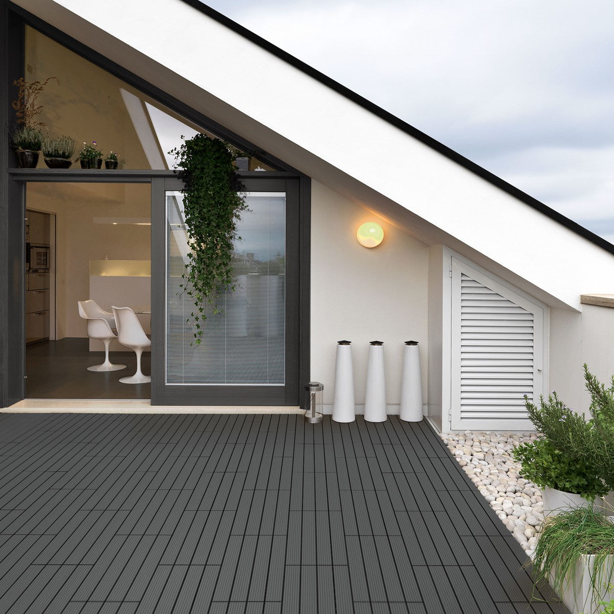 Terrazza moderna con piastrelle WPC, piante e mobili sullo sfondo.