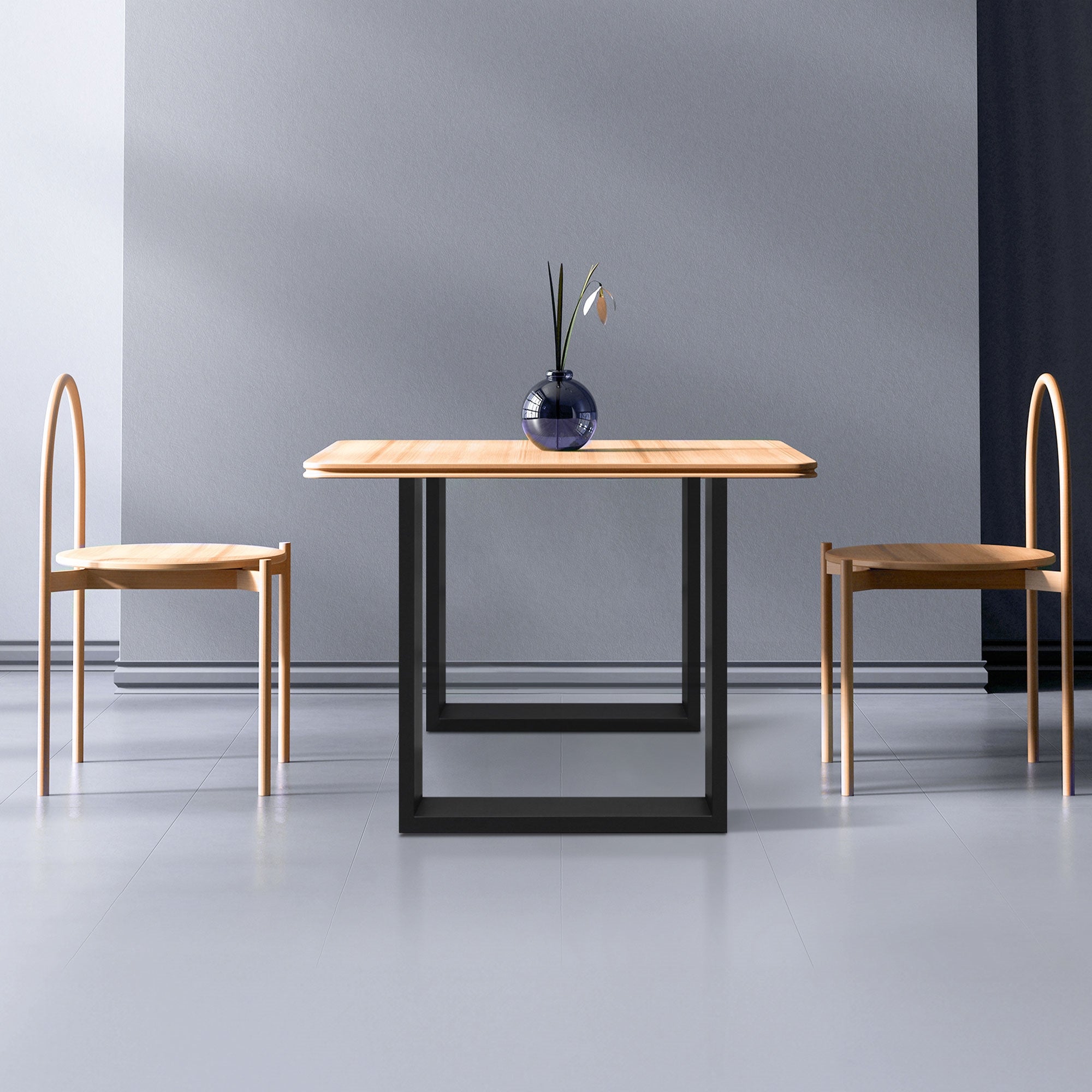 Tisch mit Holzplatte und zwei Stühlen in einem minimalistischen Raum.