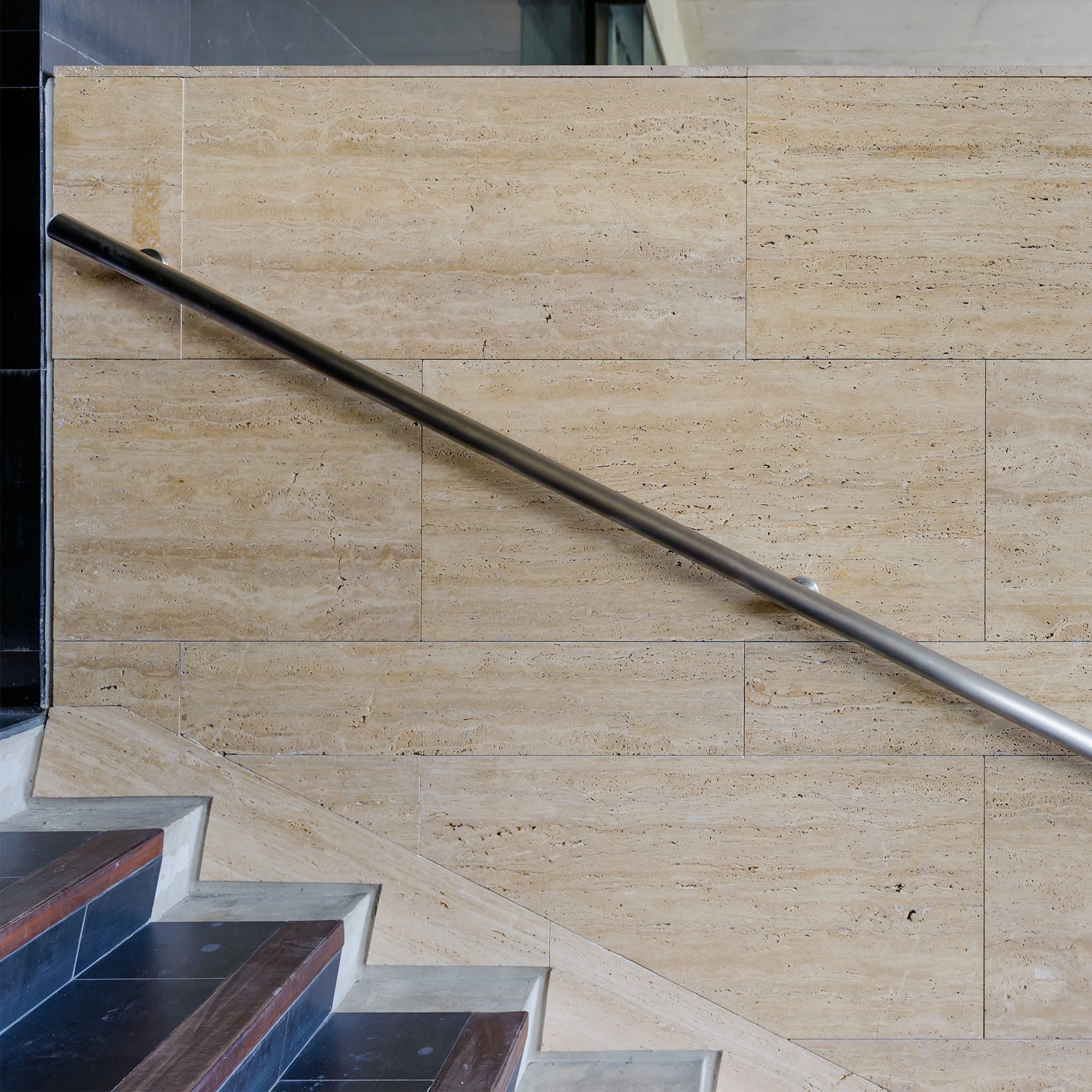 Edelstahl-Handlauf an einer Treppe mit Steinwand.
