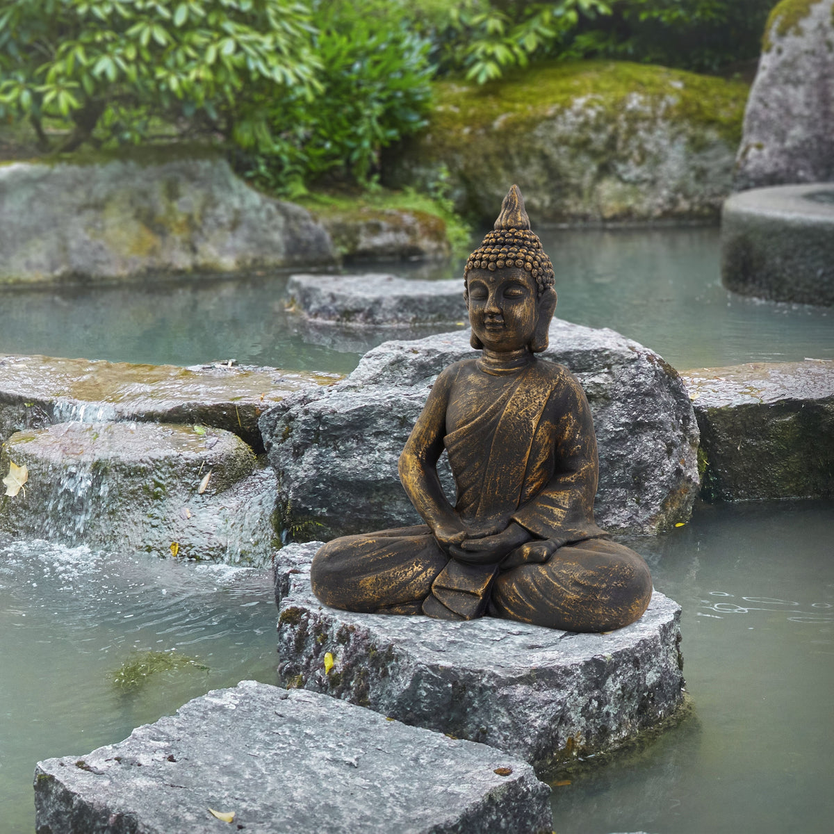 Buddha-Statue auf einem Stein in einem Garten, umgeben von Wasser und Felsen.