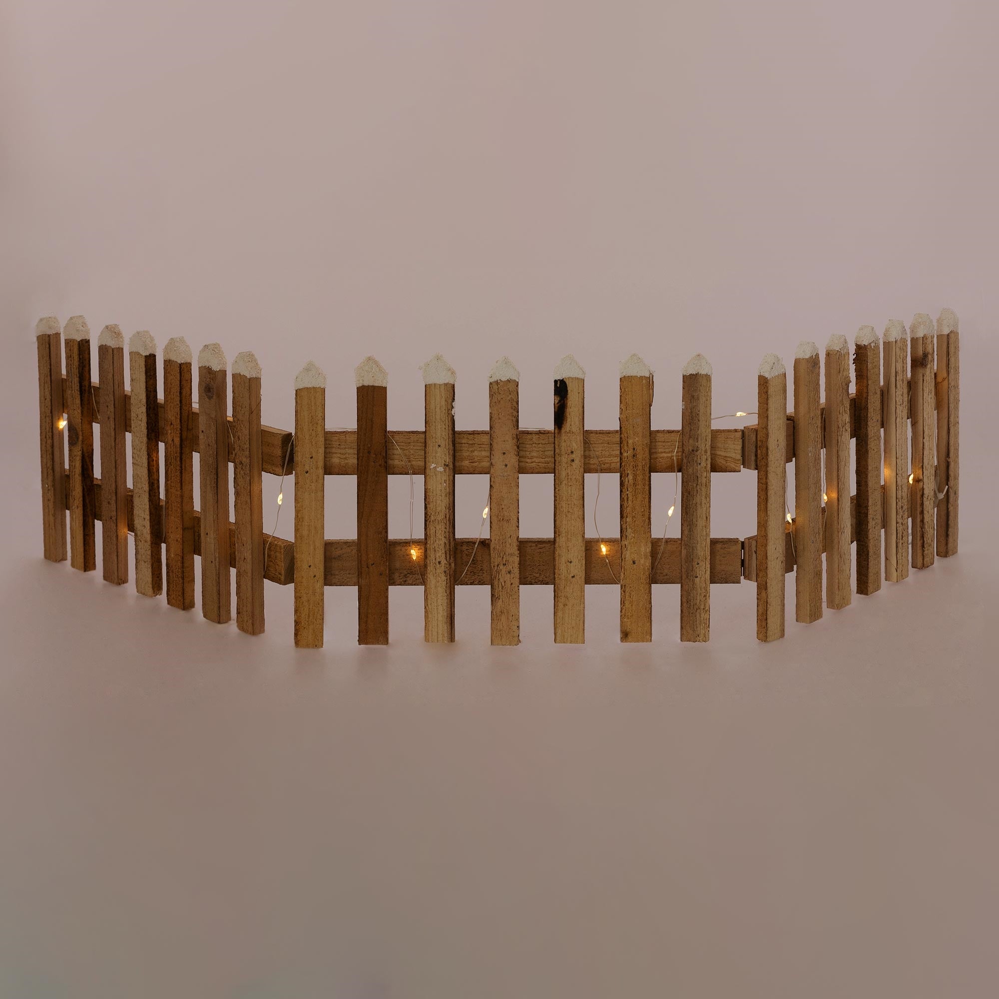 Holzzaun mit weißen Spitzen und Lichtern, auf einem einfarbigen Hintergrund.