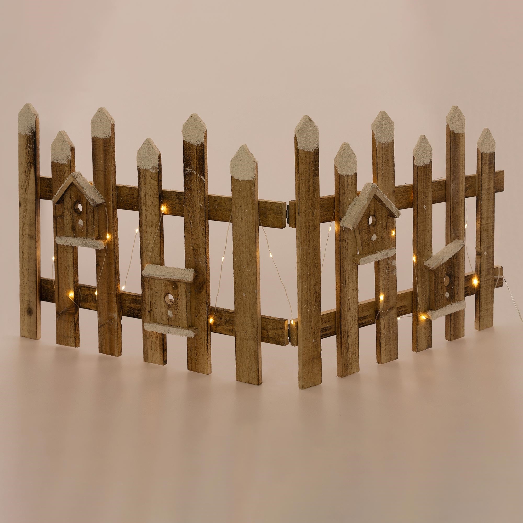 Holzlattenzaun mit kleinen Vogelhäusern und Lichtern.