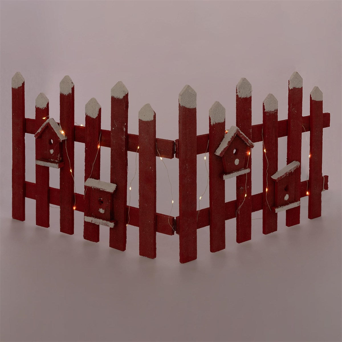 Ein roter Holzzaun mit kleinen Vogelhäusern und Lichtern.