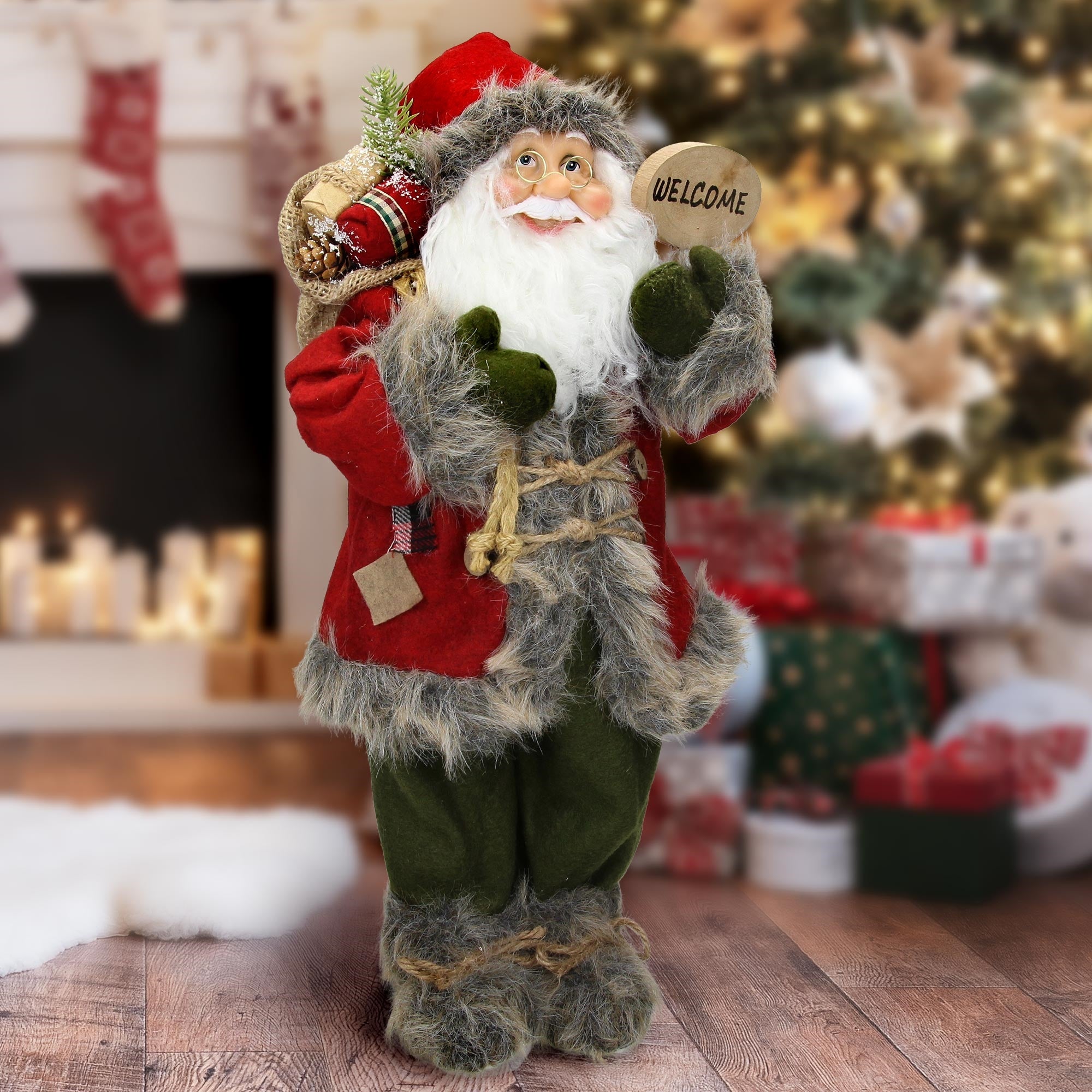 Weihnachtsmann mit Sack und Schild 'WELCOME' vor einem Weihnachtsbaum.