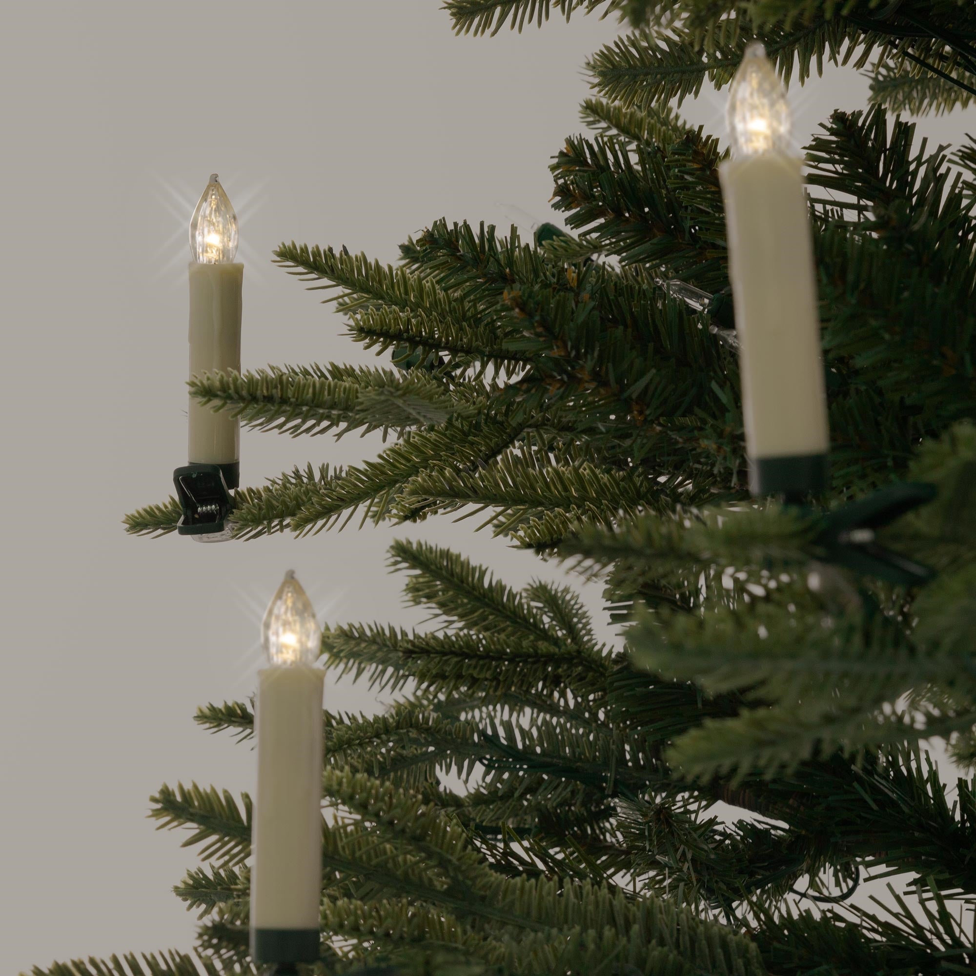 Three candle lights on a Christmas tree that are glowing.