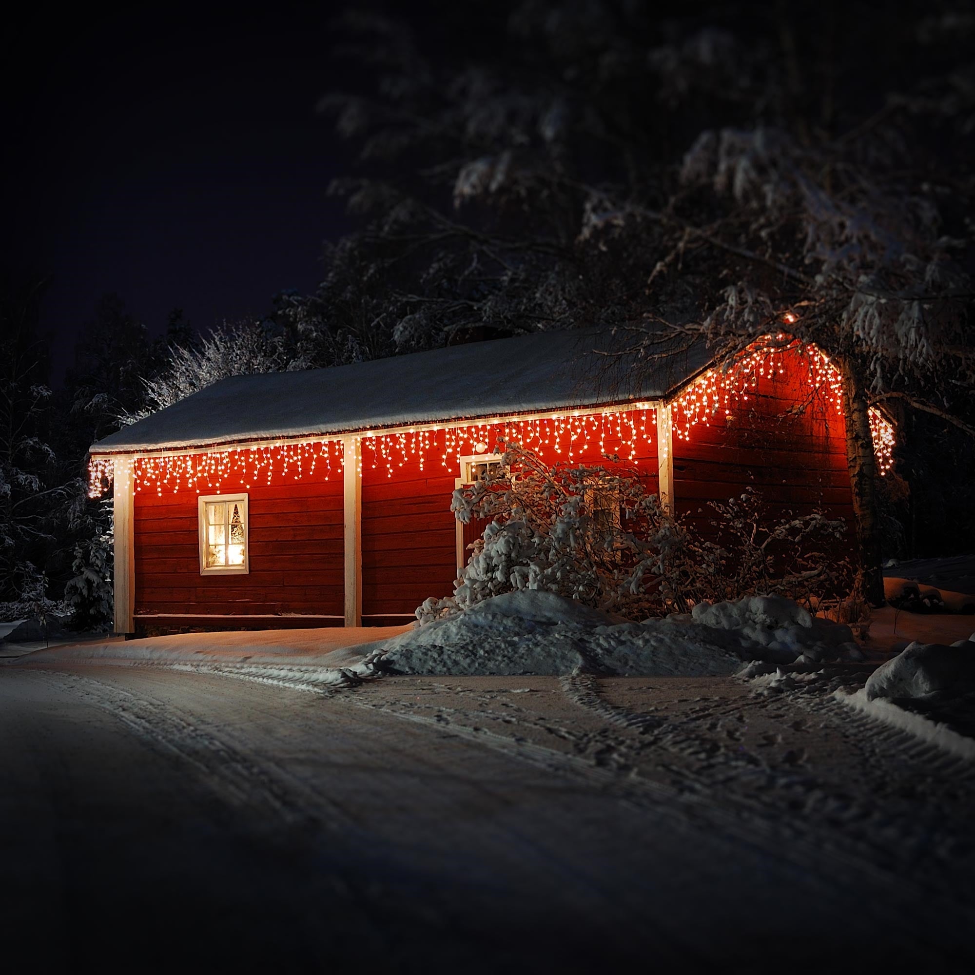 Ein rotes Haus mit Weihnachtslichtern im Schnee.