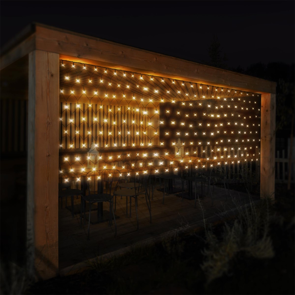 Verandă din lemn cu un perete luminat de luminițe la amurg.