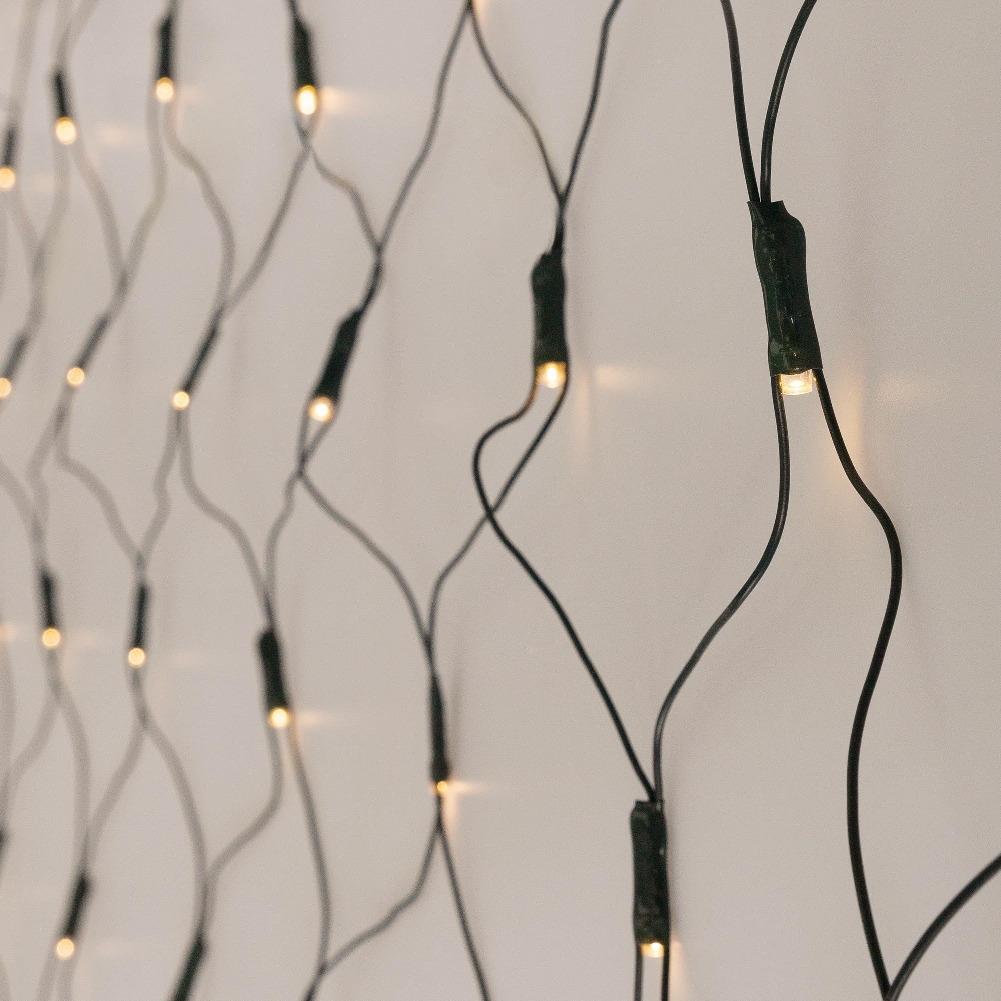 Lichterkette mit warmweißen LEDs auf hellem Hintergrund, Kabel sichtbar.