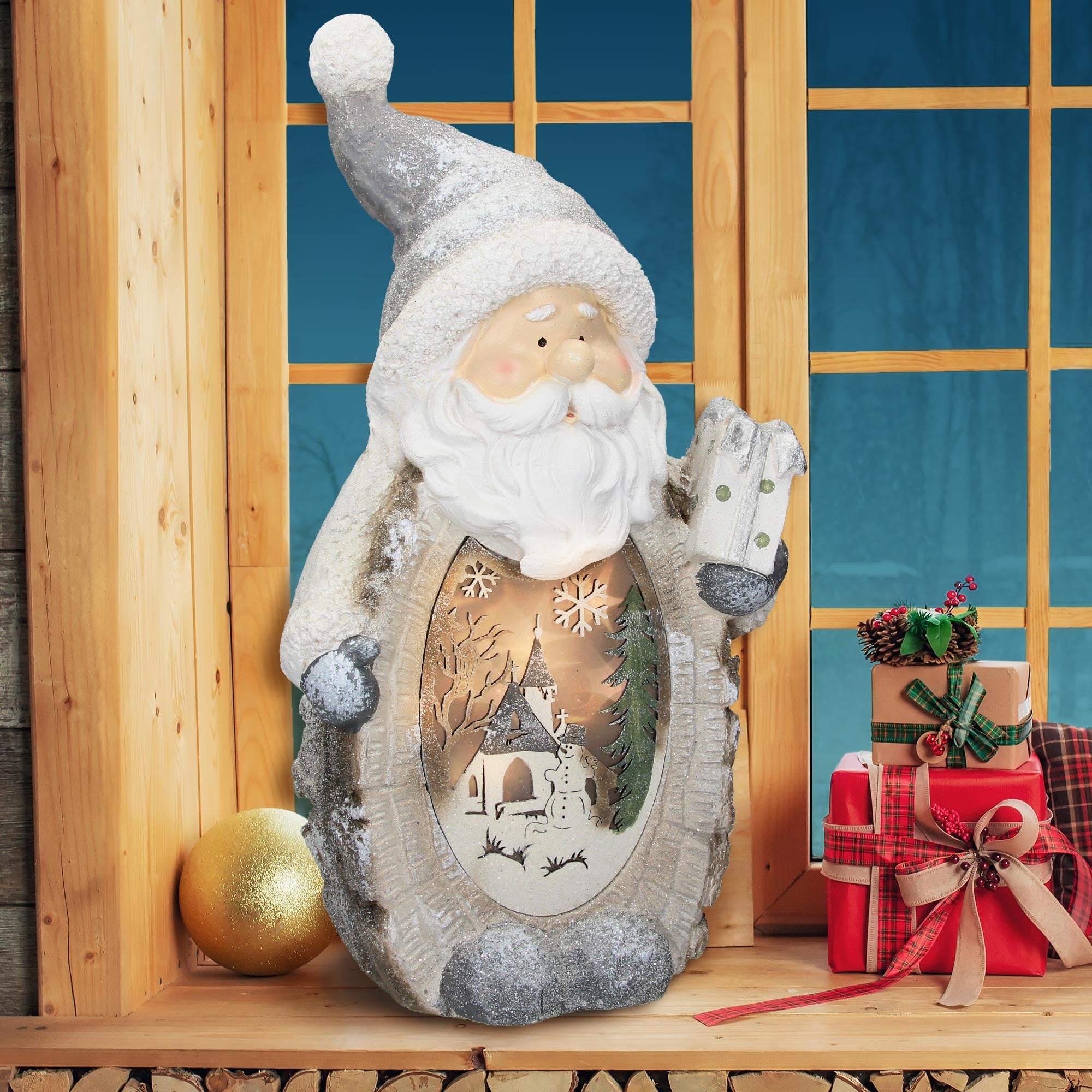 Rentierfigur mit Weihnachtsmotiven, steht vor einem Fenster und Geschenken.