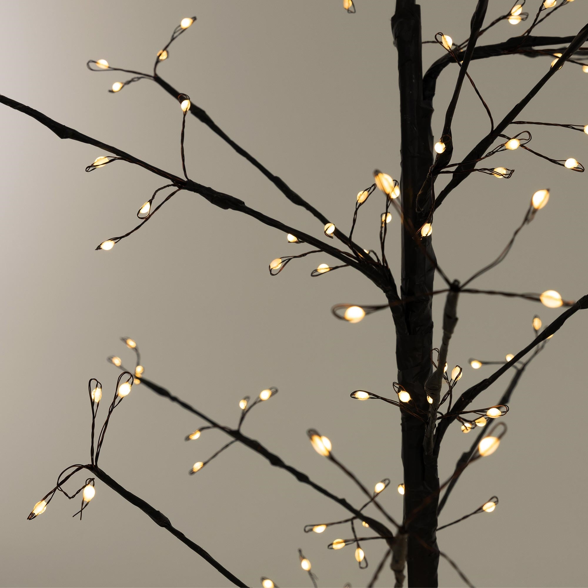 Primer plano de un árbol artificial con luces cálidas en las ramas.