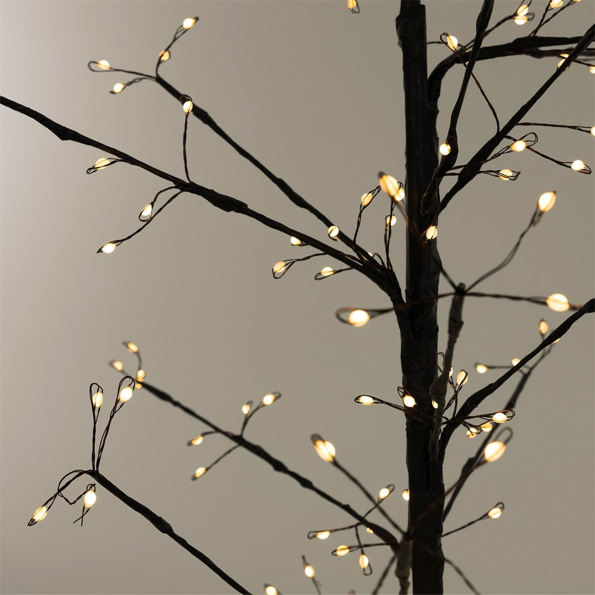 Detailaufnahme eines künstlichen Baumes mit warmen Lichtern an den Zweigen.