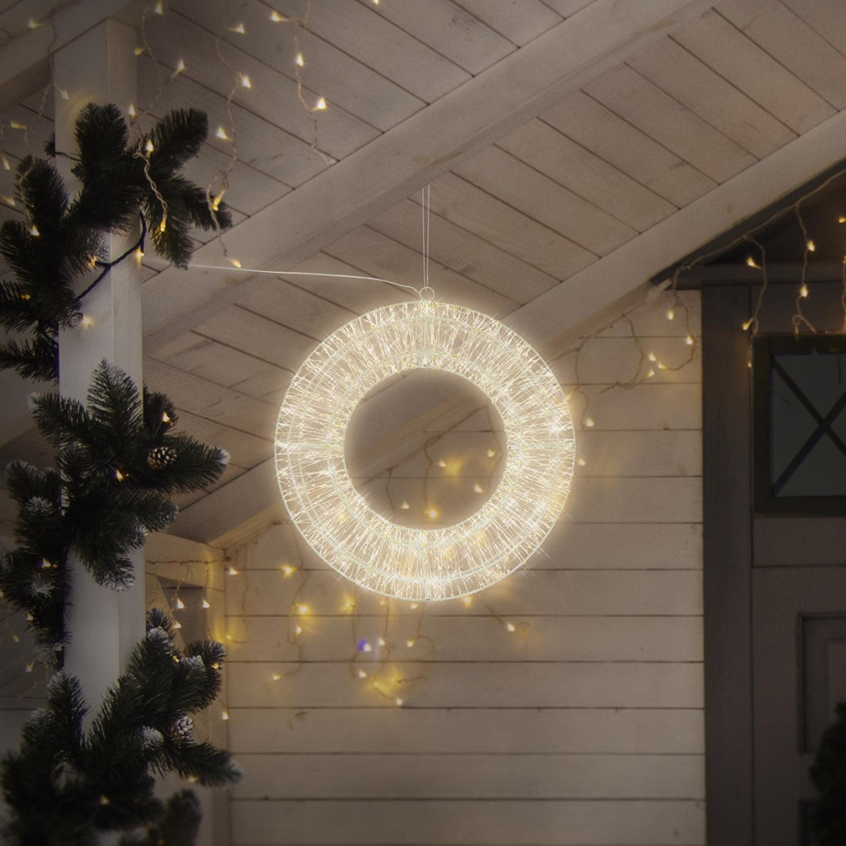 Couronne lumineuse et ronde suspendue dans une pièce décorée pour Noël.