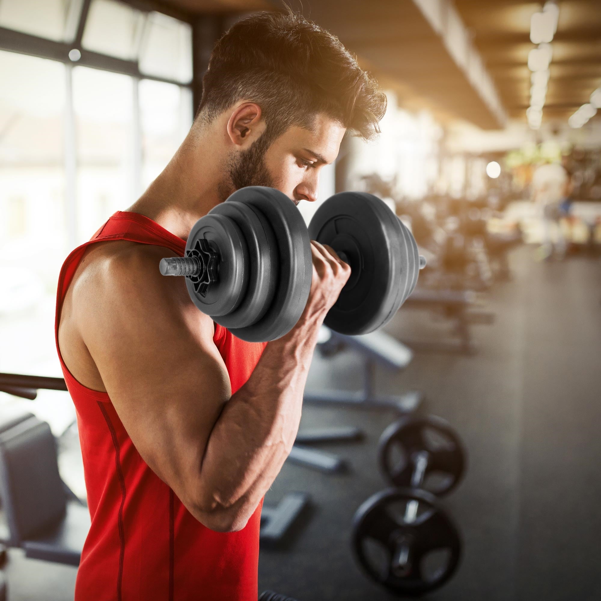 Homme avec haltère dans une salle de sport, entraîne son biceps.