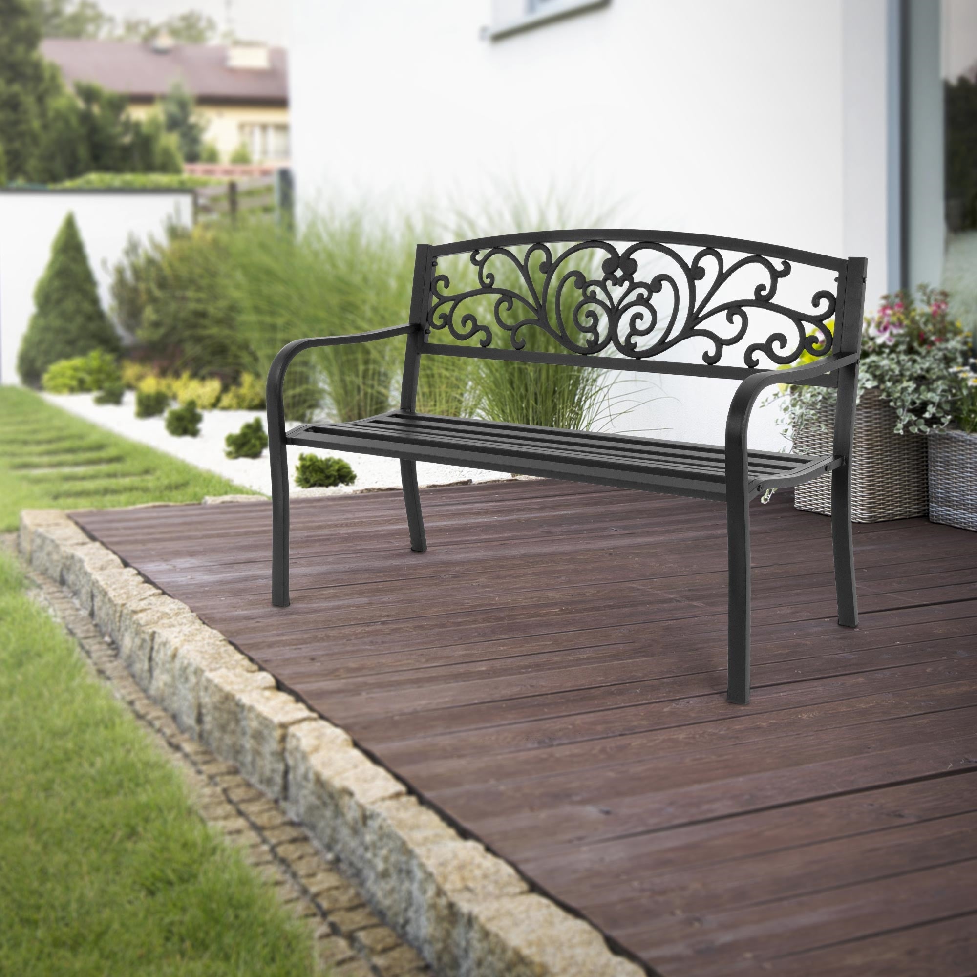 Black bench with curved design on a wooden terrace in the garden.