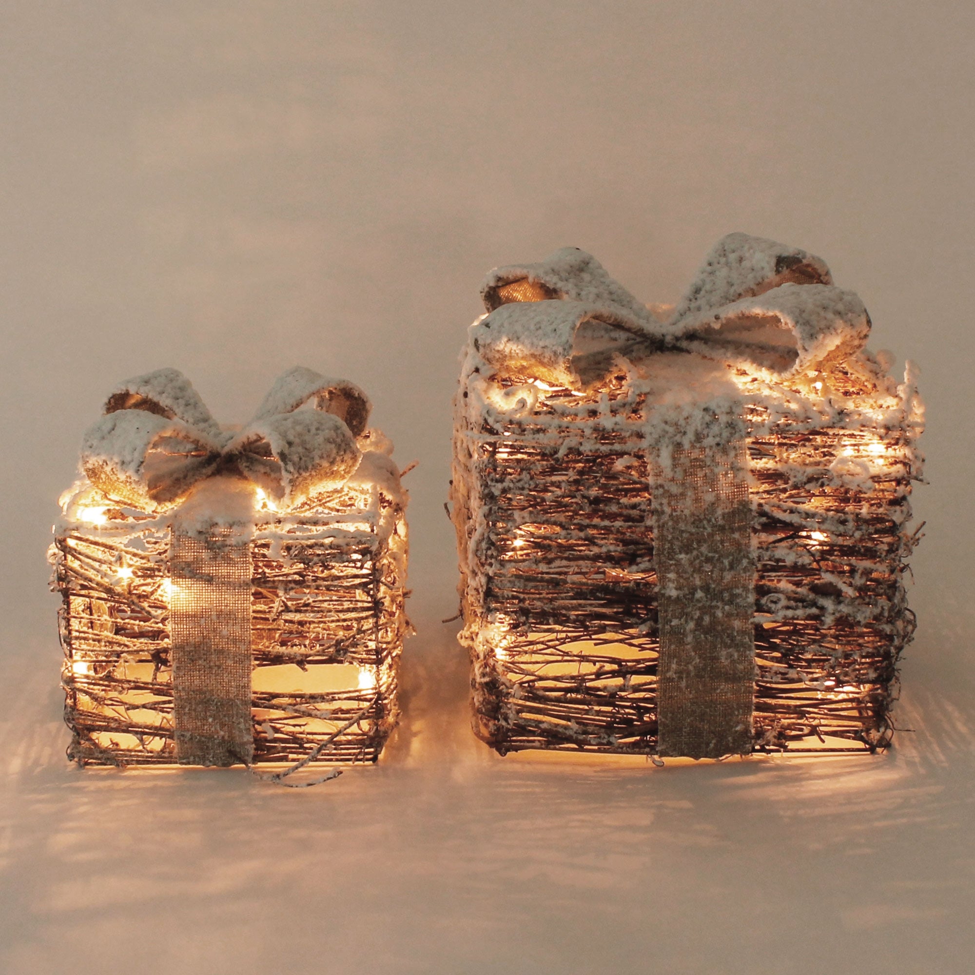 Dos regalos de ramas con lazos y luces.