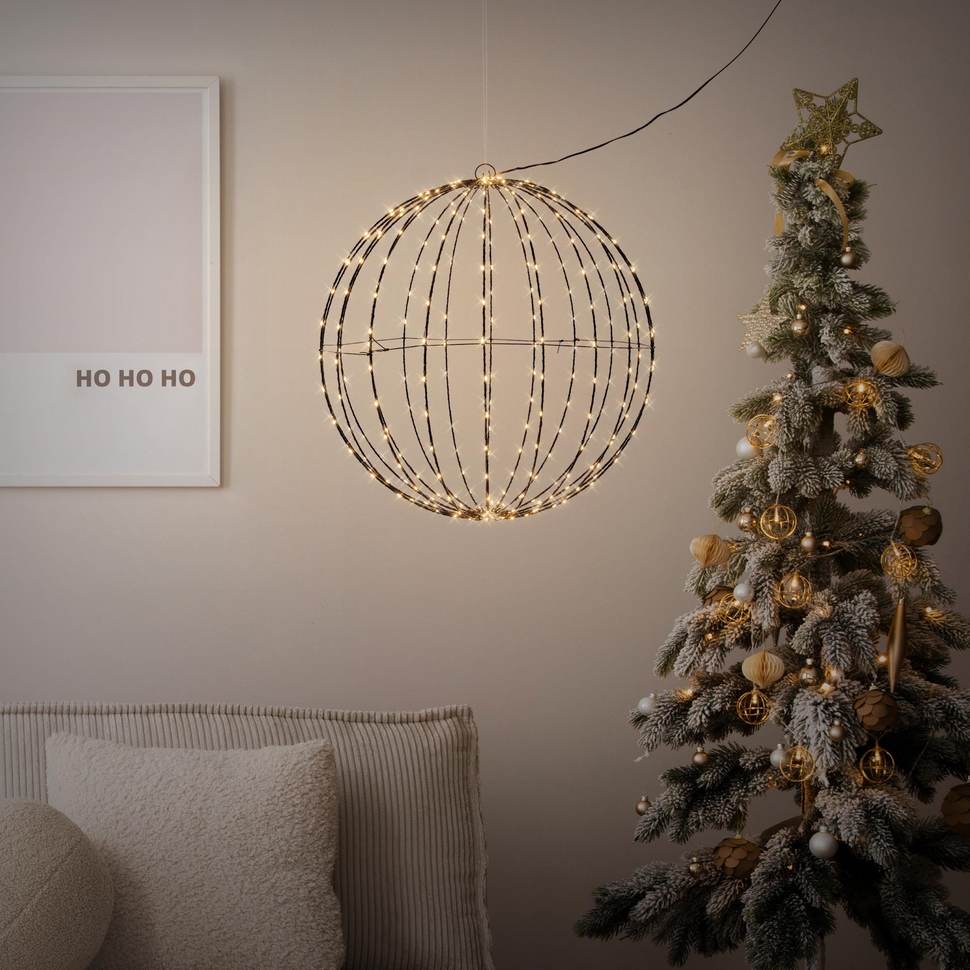 Une décoration ronde éclairée suspendue au-dessus d'un sapin de Noël.