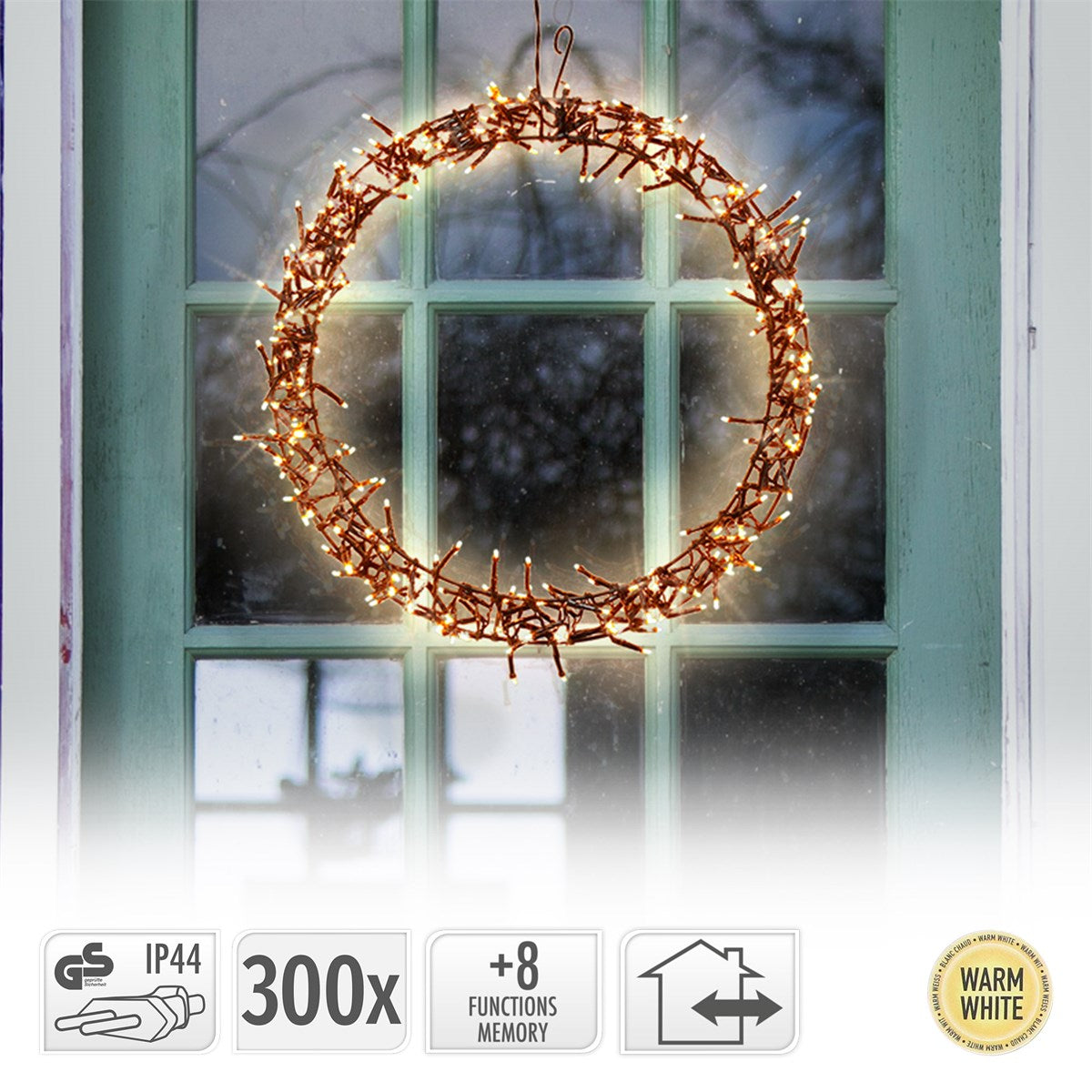 Ein runder Kranz aus Zweigen mit warmweißen Lichtern, hängt vor einem Fenster.