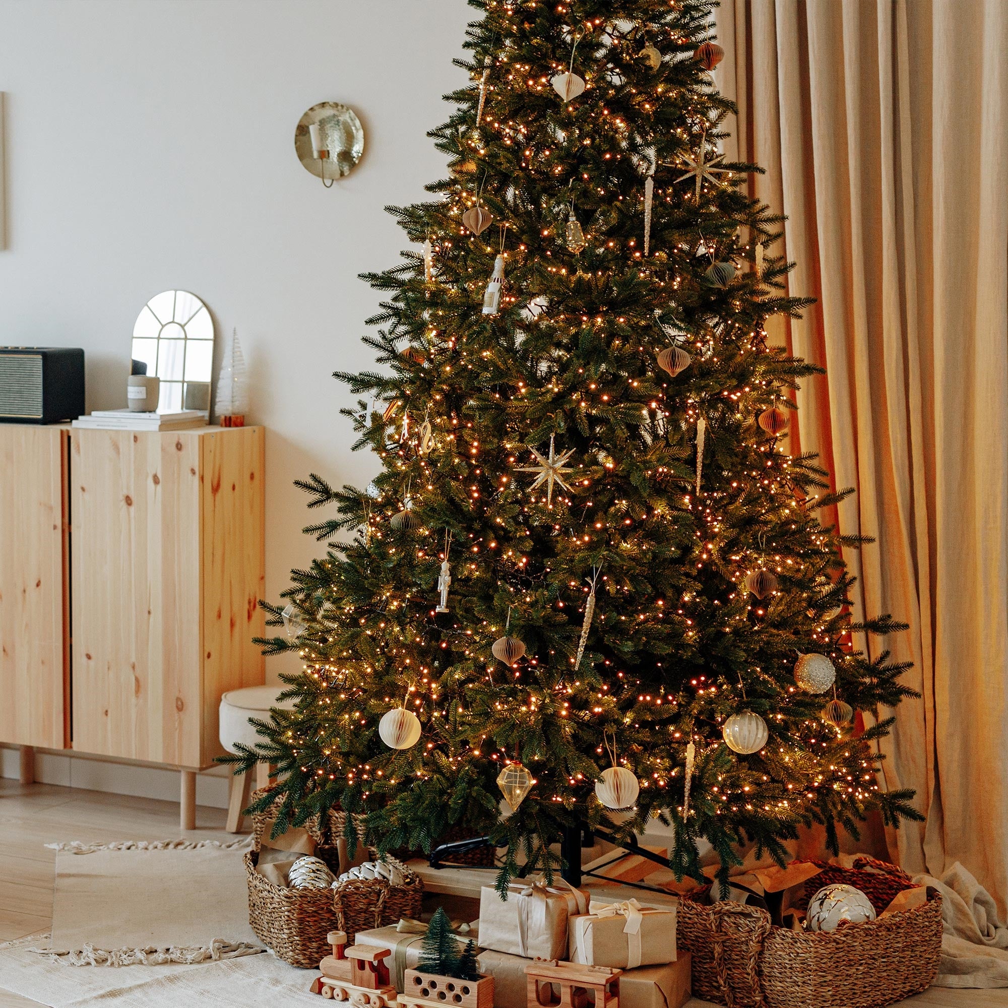Kerstboom met lichten en cadeaus eronder in een kamer.