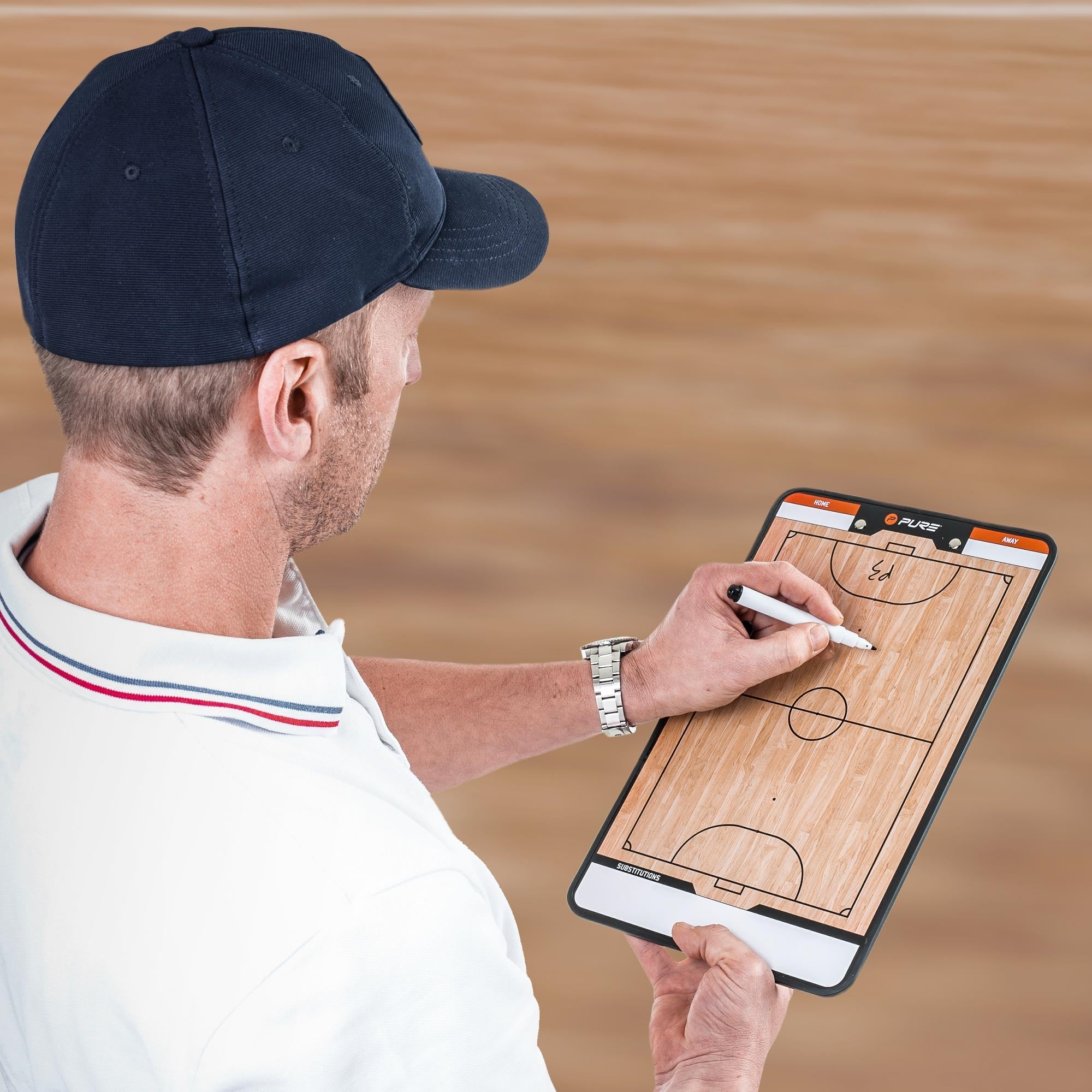 A coach is writing on a basketball tactics board with a pen.