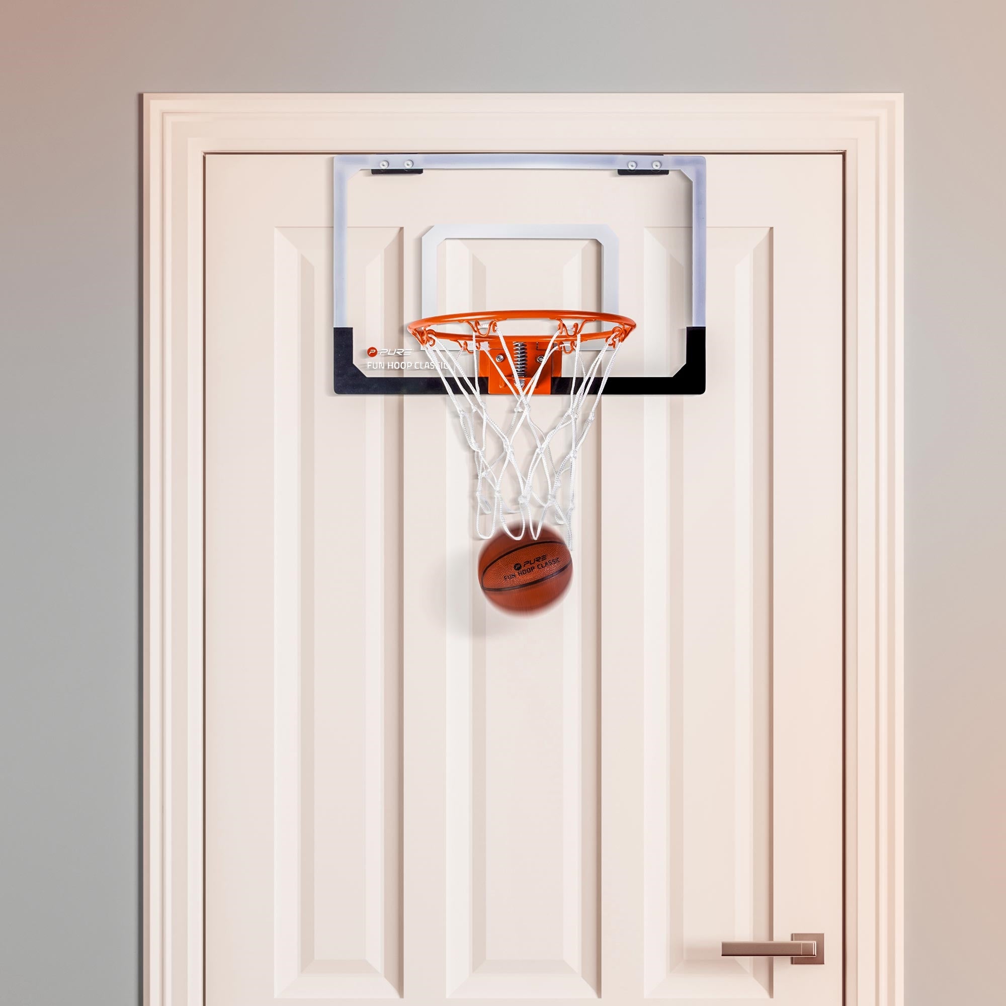 Basketballkorb an einer Tür mit einem Basketball, der im Netz hängt.