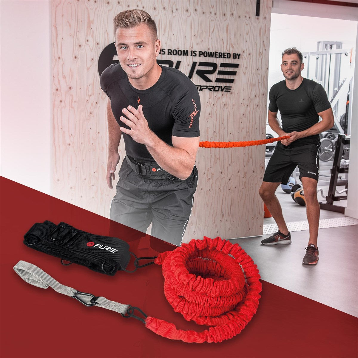 Dva muži trénují s elastickým odporovým pásem ve fitness centru.