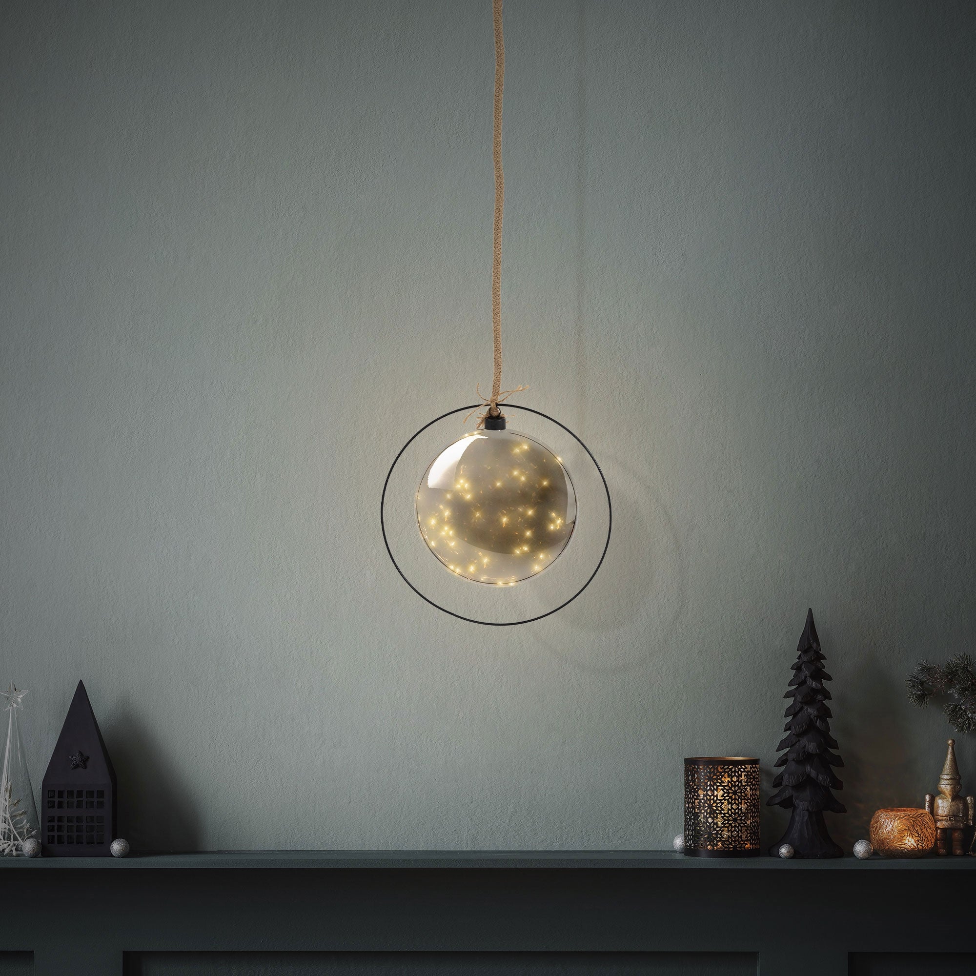 Hanging glass ball with lights against a gray wall.