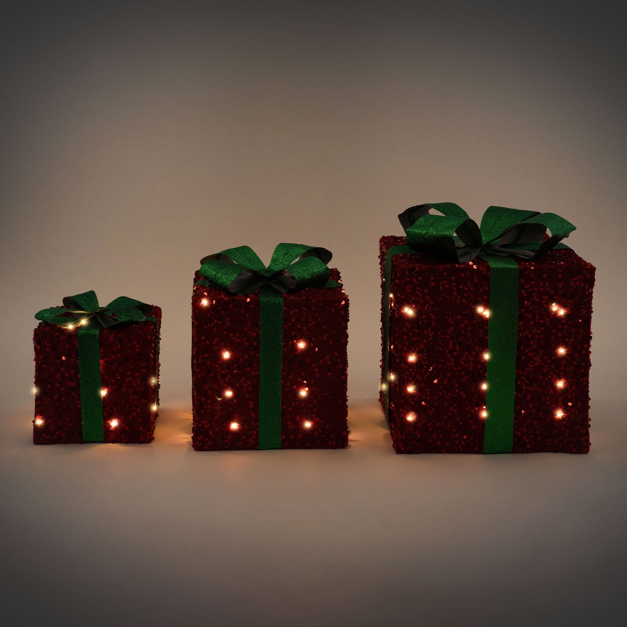 Drei leuchtende Geschenke in verschiedenen Größen mit grünen Schleifen.