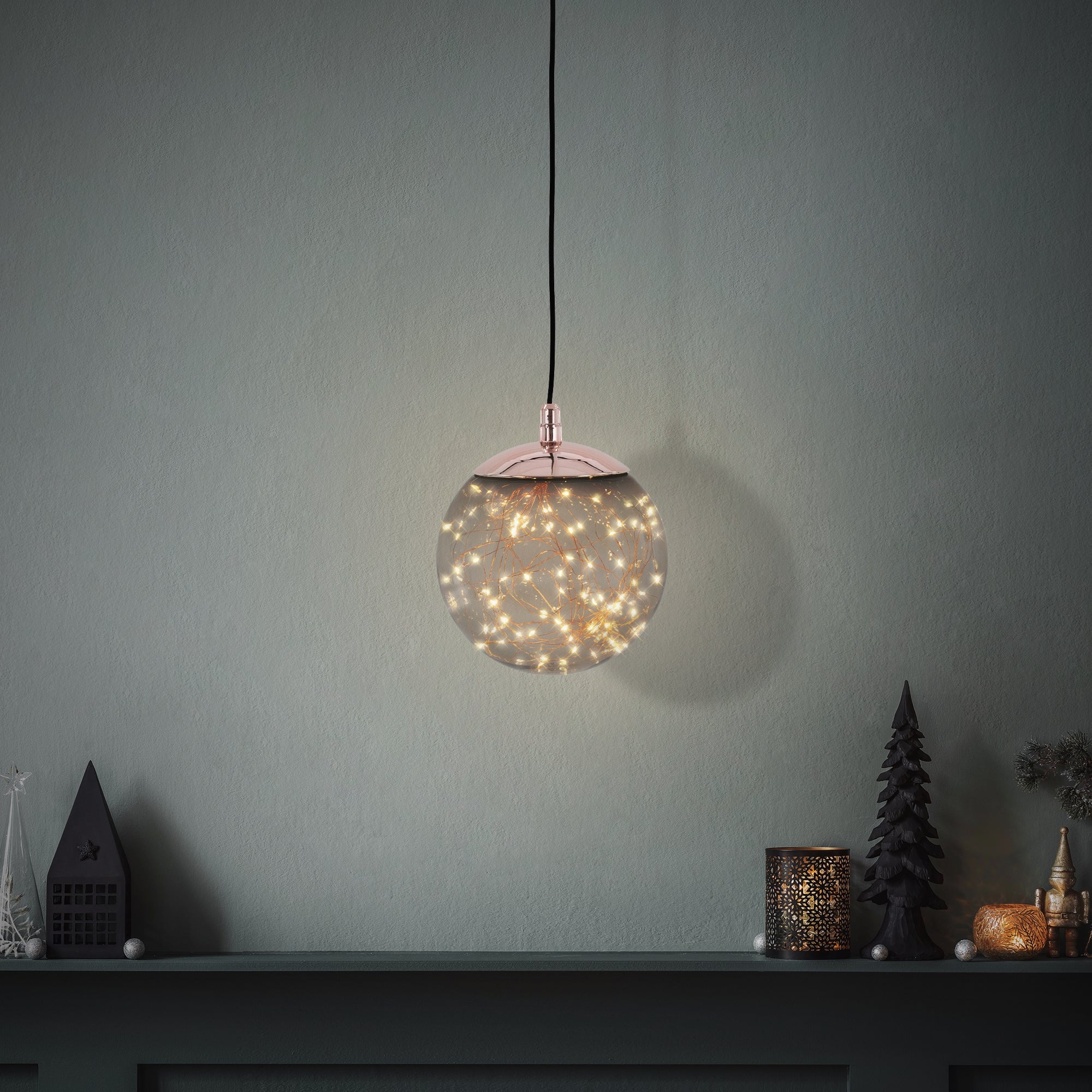 Eine hängende Glaskugel mit Lichtern vor einer Wand und Dekoration.