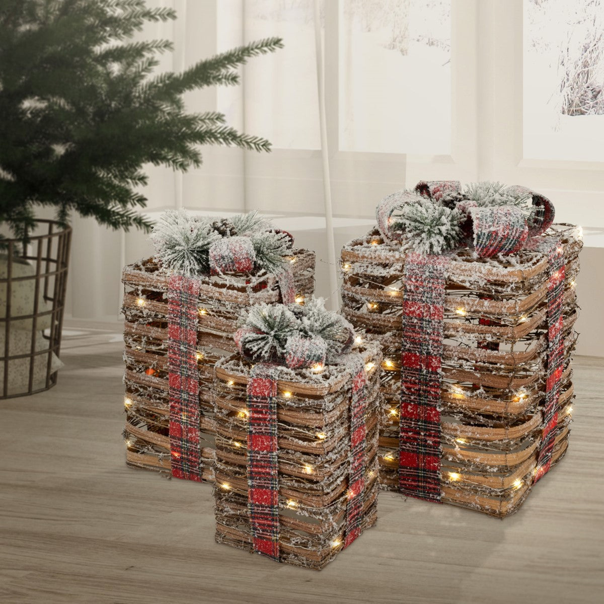 Zwei gestapelte Holzkisten als Geschenke, mit roten Karobändern, Tannenzweigen und warmweißen Lichtern dekoriert.