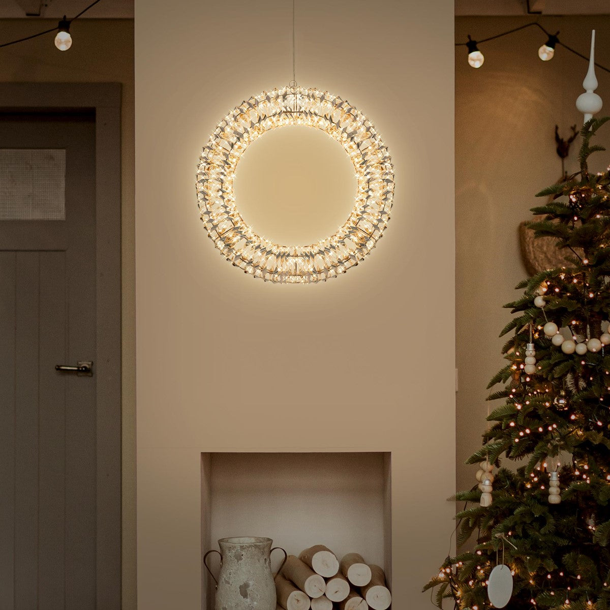 Lichtkranz an Wand, neben einem Weihnachtsbaum und dekorativen Elementen.