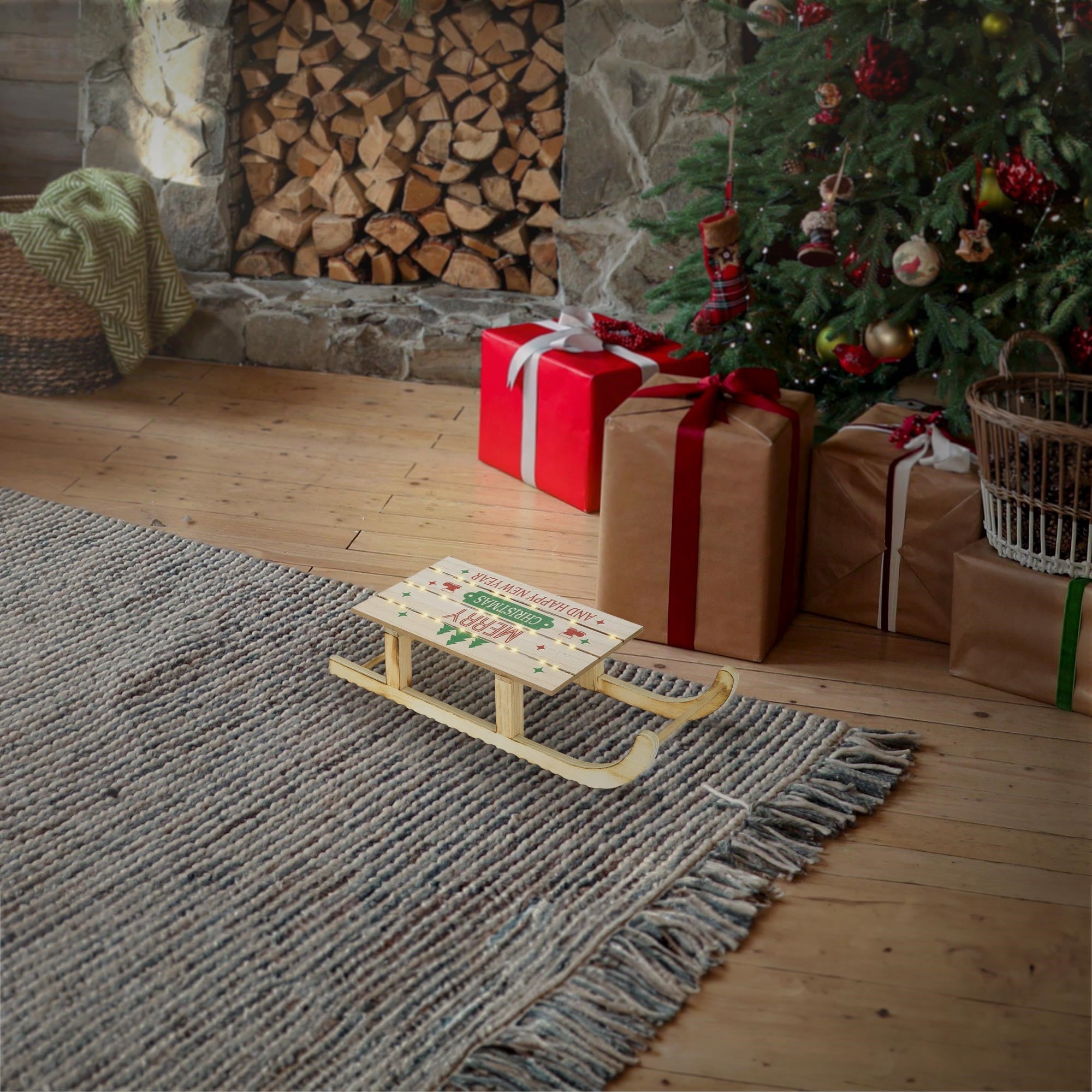 Slitta di legno davanti a un albero di Natale e regali in una stanza accogliente.