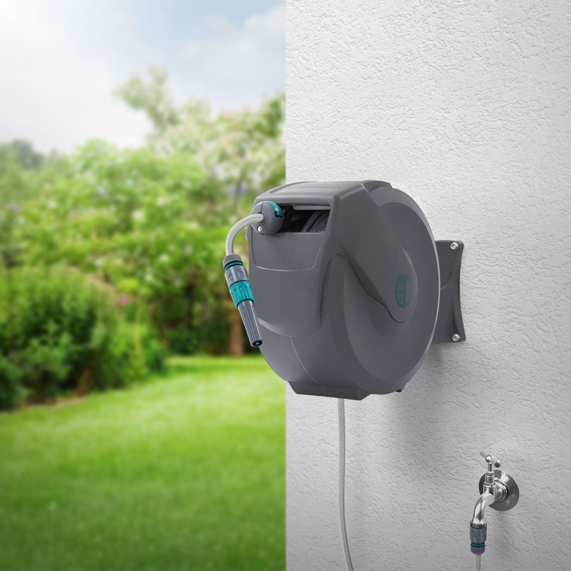 Wasserrolle mit Schlauch, an einer Wand montiert, im Freien mit grünem Garten.